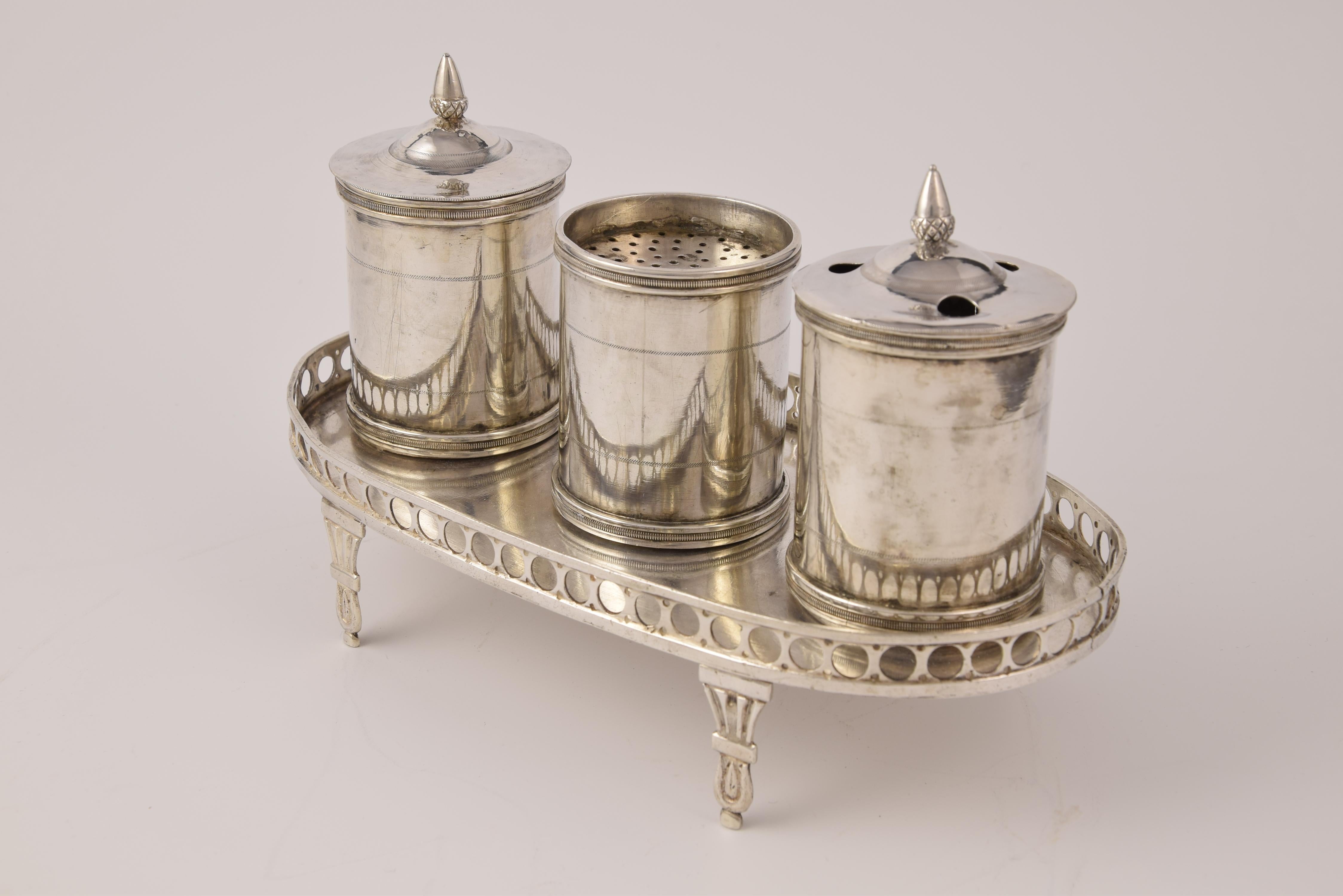 With hallmarks.
On an oval tray decorated with an openwork balustrade, are placed various items: the inkwell, the sandpit and container with lid holed to let the feathers on, all similar and decorated very simply with inspiration from the