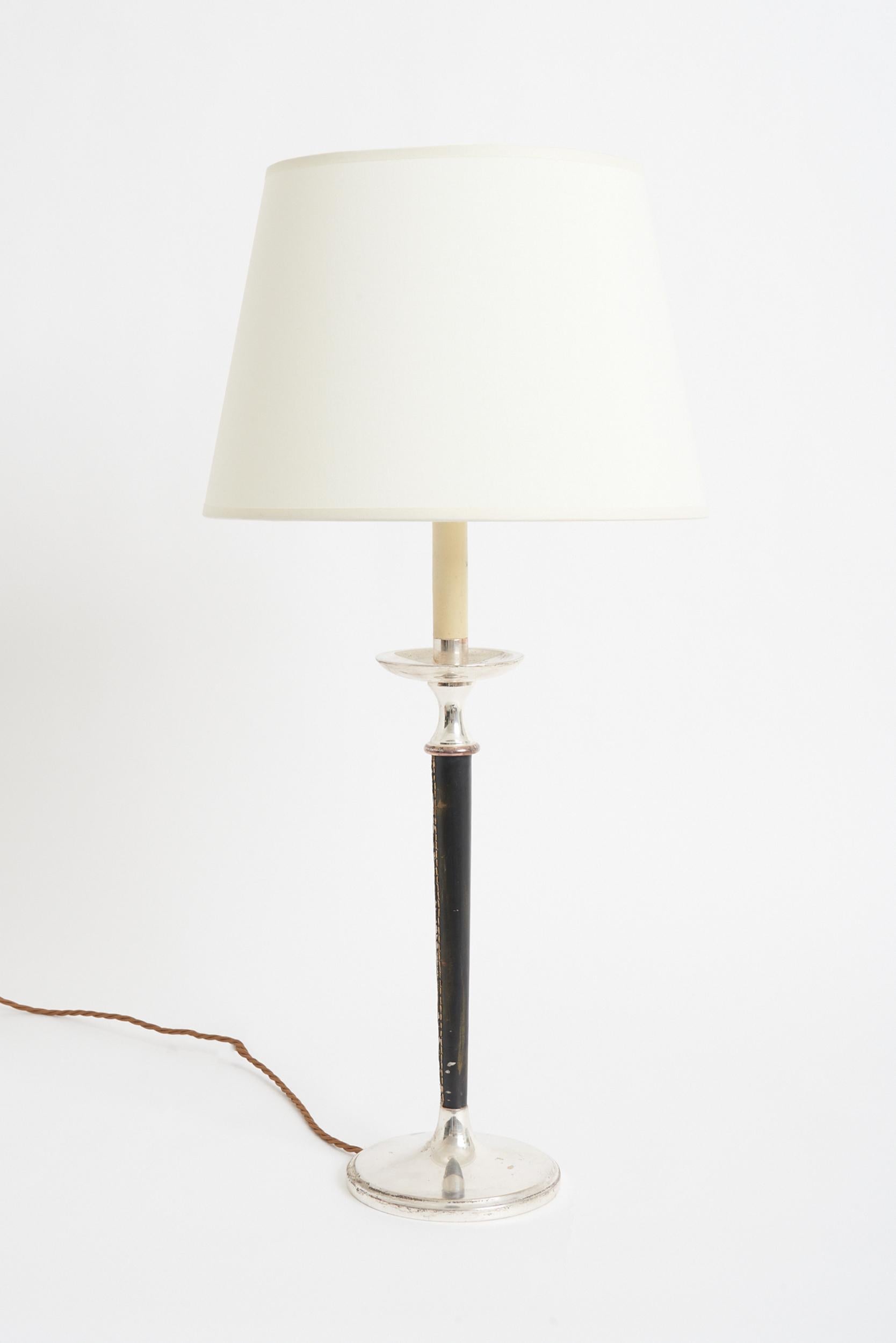 A black leather and silver plated table lamp.
France, third quarter of the 20th century.
With the shade: 73 cm high by 35.5 cm diameter
Lamp base only: 55 cm high by 16 cm diameter.