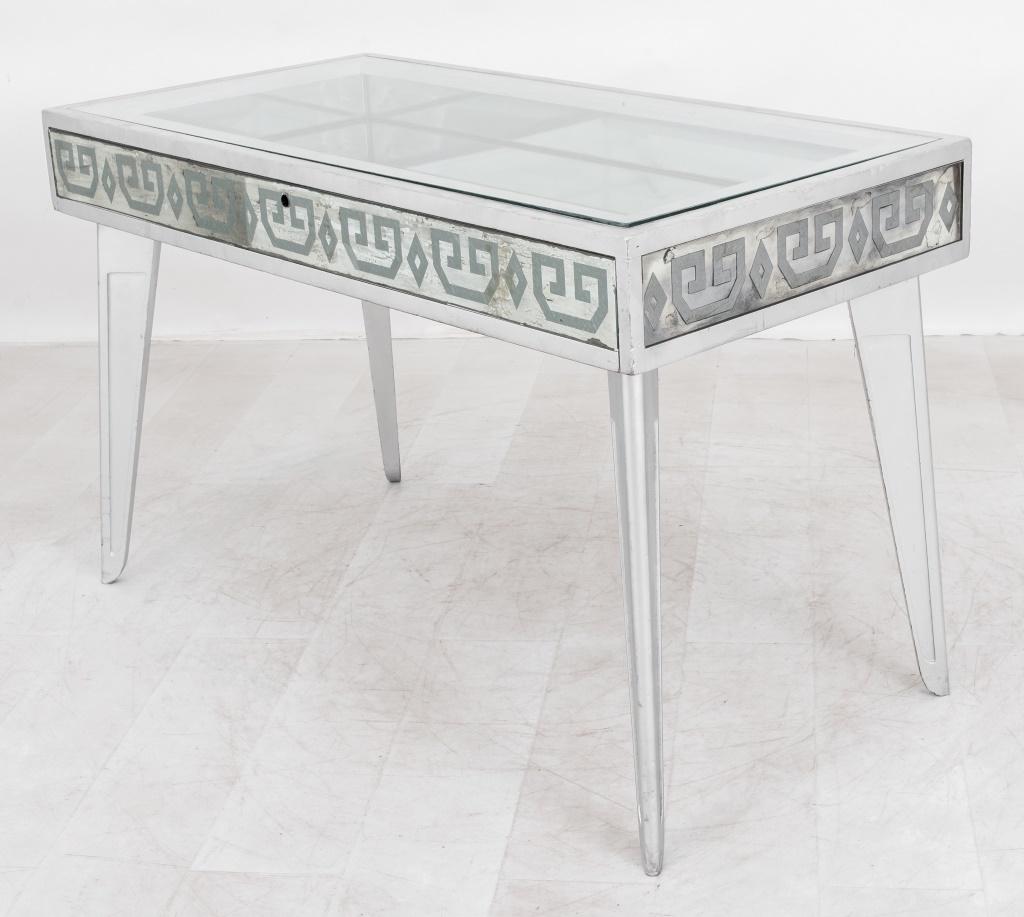 Silvered Art Deco or Art Moderne Vitrine Table, circa 1940s, with rectangular glass top and mirrored interior, the whole with a Greek key or meander decorated reverse painted glass frieze above splayed silver legs. 
Dimensions: 30