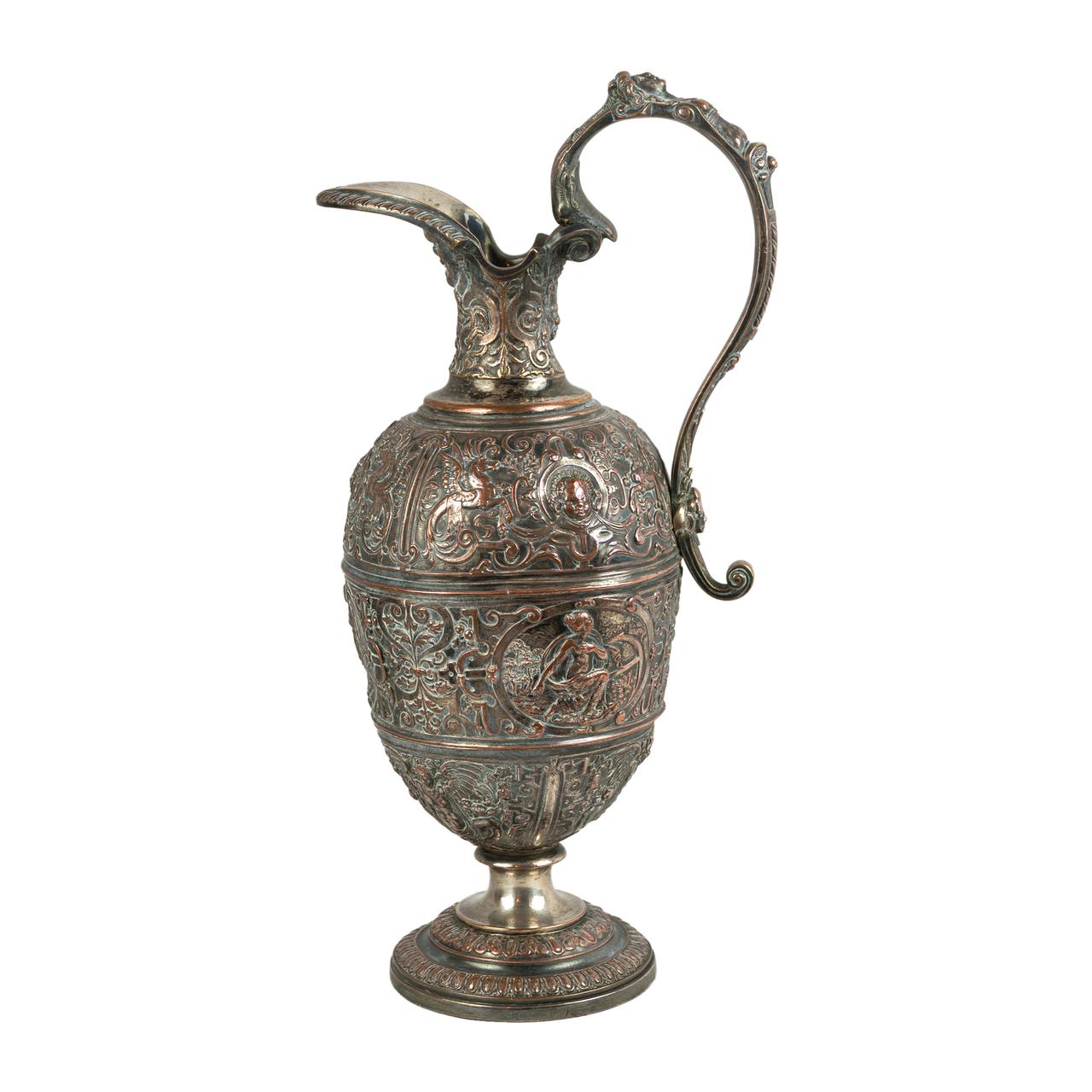 It features Renaissance Revival chased decoration all over, with strapwork, masks, arabesques, foliage and animals against a matte silver background. The body has three banded sections, each with its own motifs. The tall neck compliments the deeply