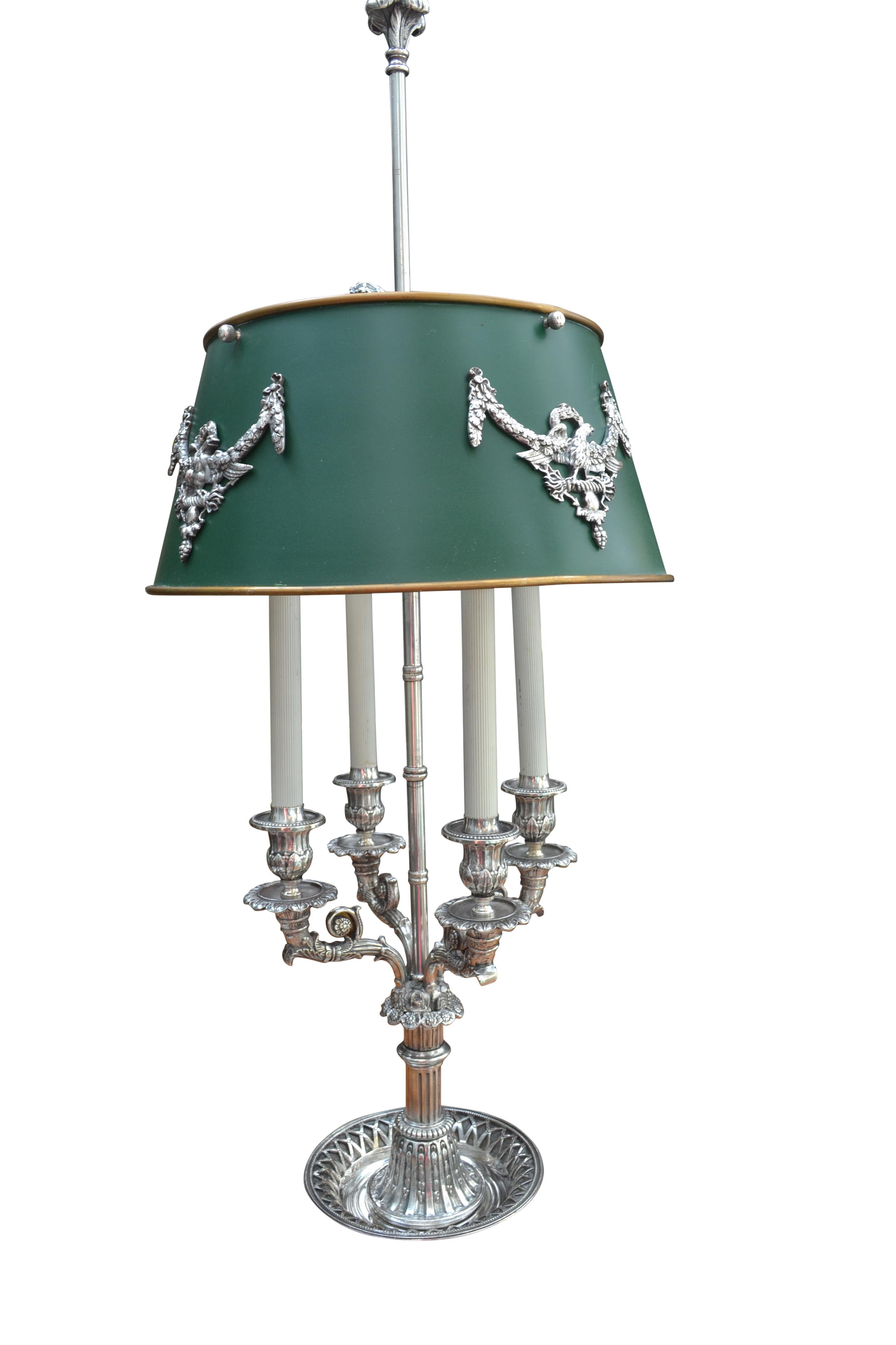 A fine example of a French Empire bouillotte lamp made of silvered bronze. The circular base supports four decorative candle arms with nozzles; the main stem of the lamp holds the electrics as well as the moveable green tole shade which has four