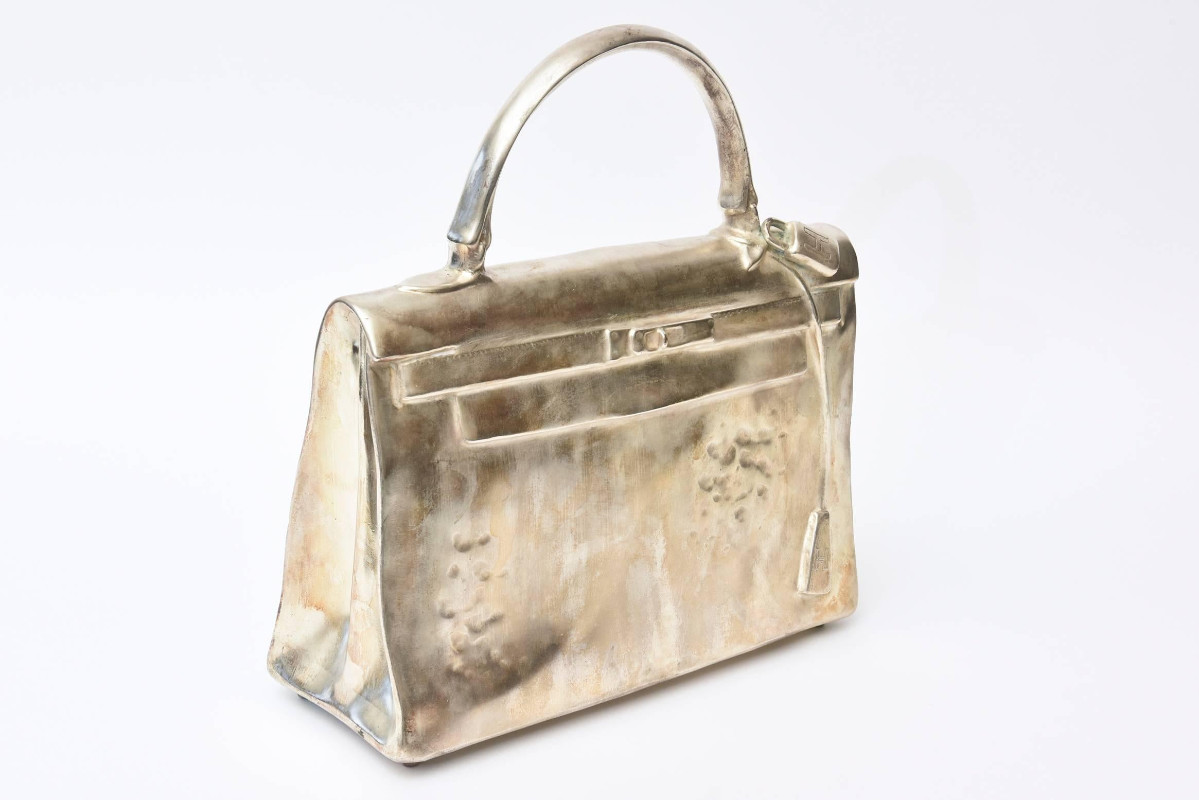 This amazing sculpture by the well known French artist and sculptor, Christian Maas is a silvered bronze life-size rendering of the infamous Hermes Kelly Birkin bag. It was a limited edition of 100. It was done in 1990. It is titled the 