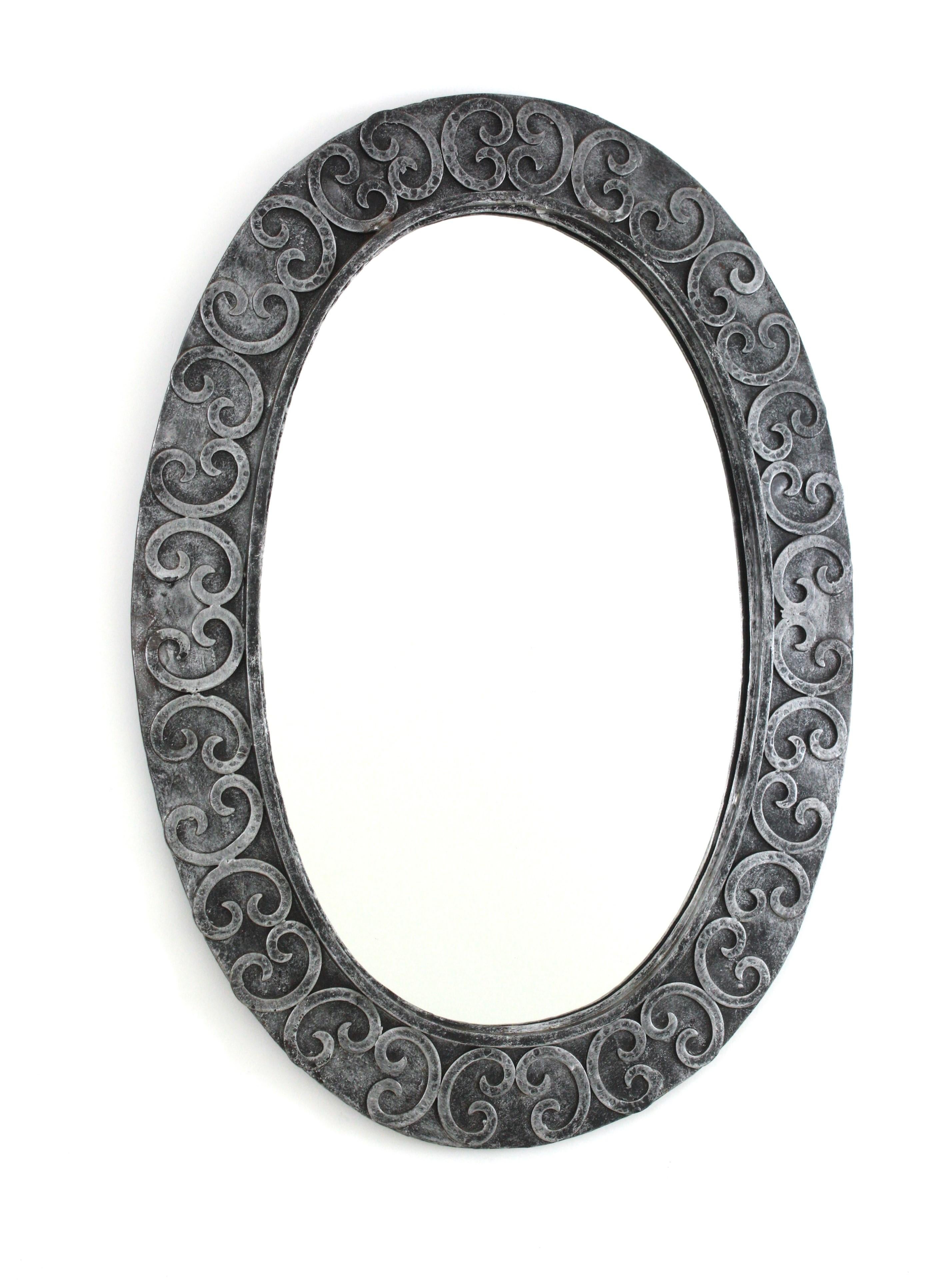 Silvered Oval Mirror in Wrought Iron
Wrought Iron Oval Wall Mirror with Scroll Details on the Frame, Spain, 1950-1960
Eye-catching hand forged iron mirror heavily adornen by scrollwork decoration on the oval frame surface.
This beautiful oval mirror