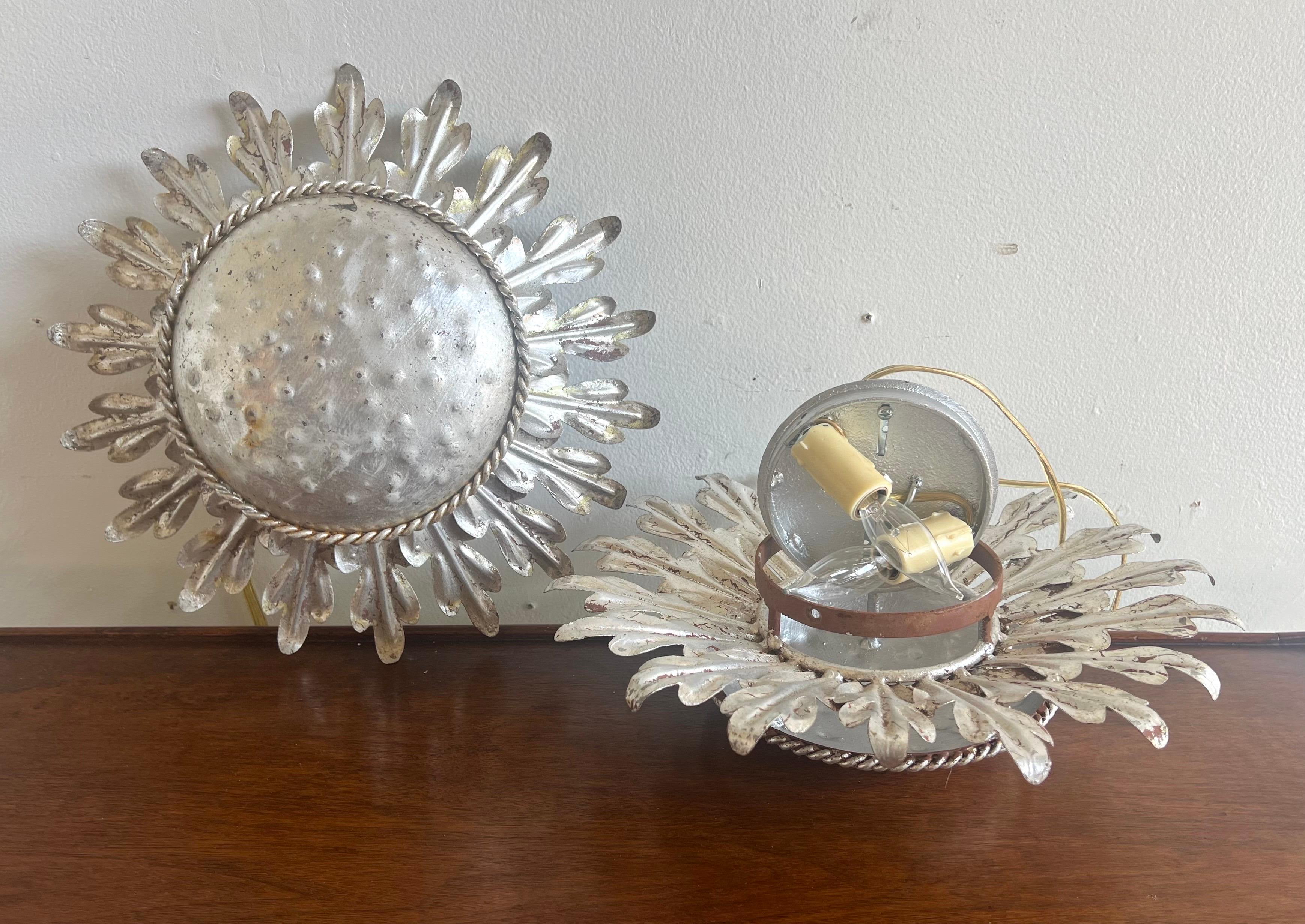 Custom silver gilt-metal ceiling light with a sunburst design.  The fixture features a central round, hammered metal plate with a rope-like border.  Surrounding the center plate are metal arms radiating outward, give the fixture a sunburst