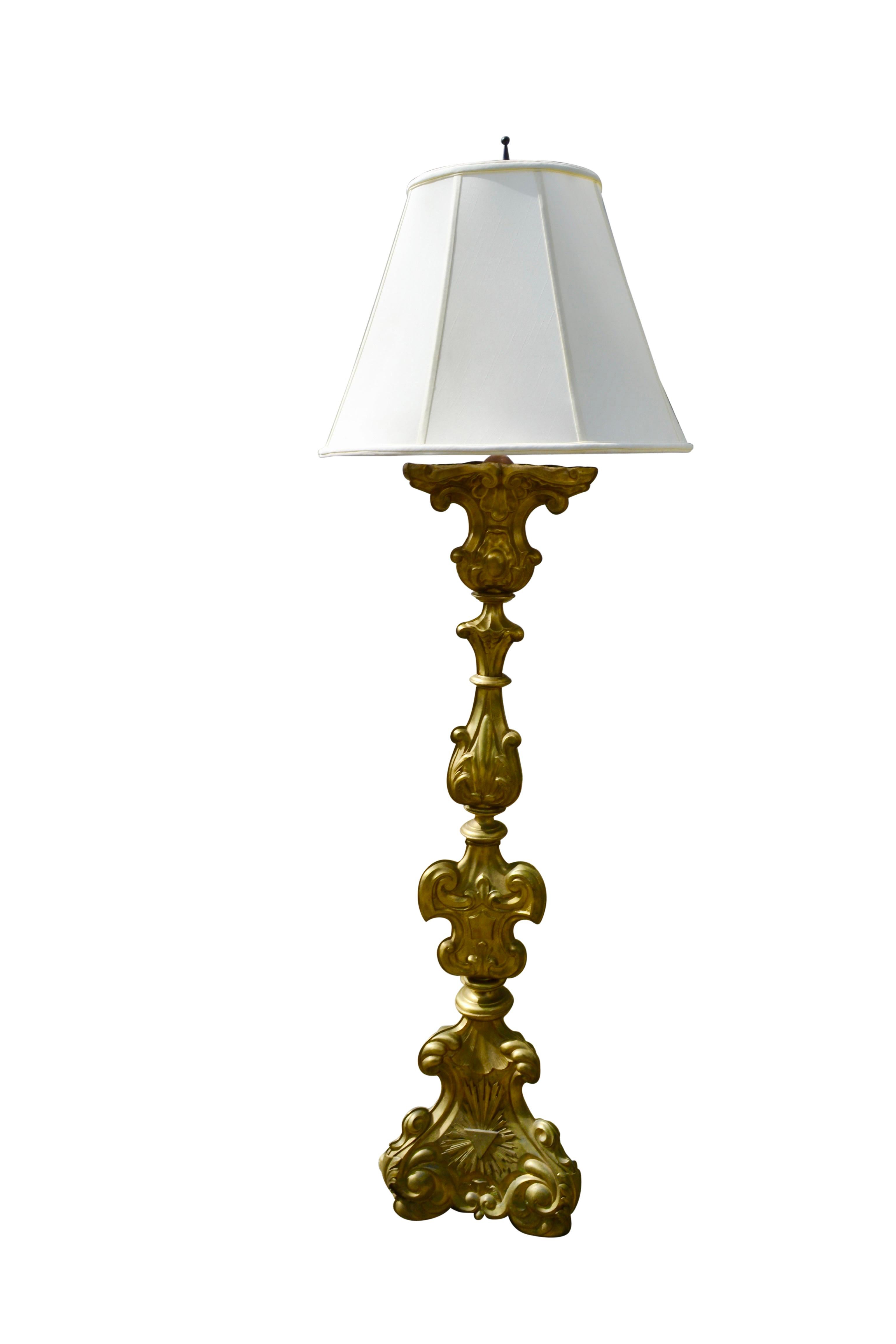 A mid-19 century French church altar candlestick made of wood clad with silvered metal in the Baroque style that has been converted into a floor lamp.