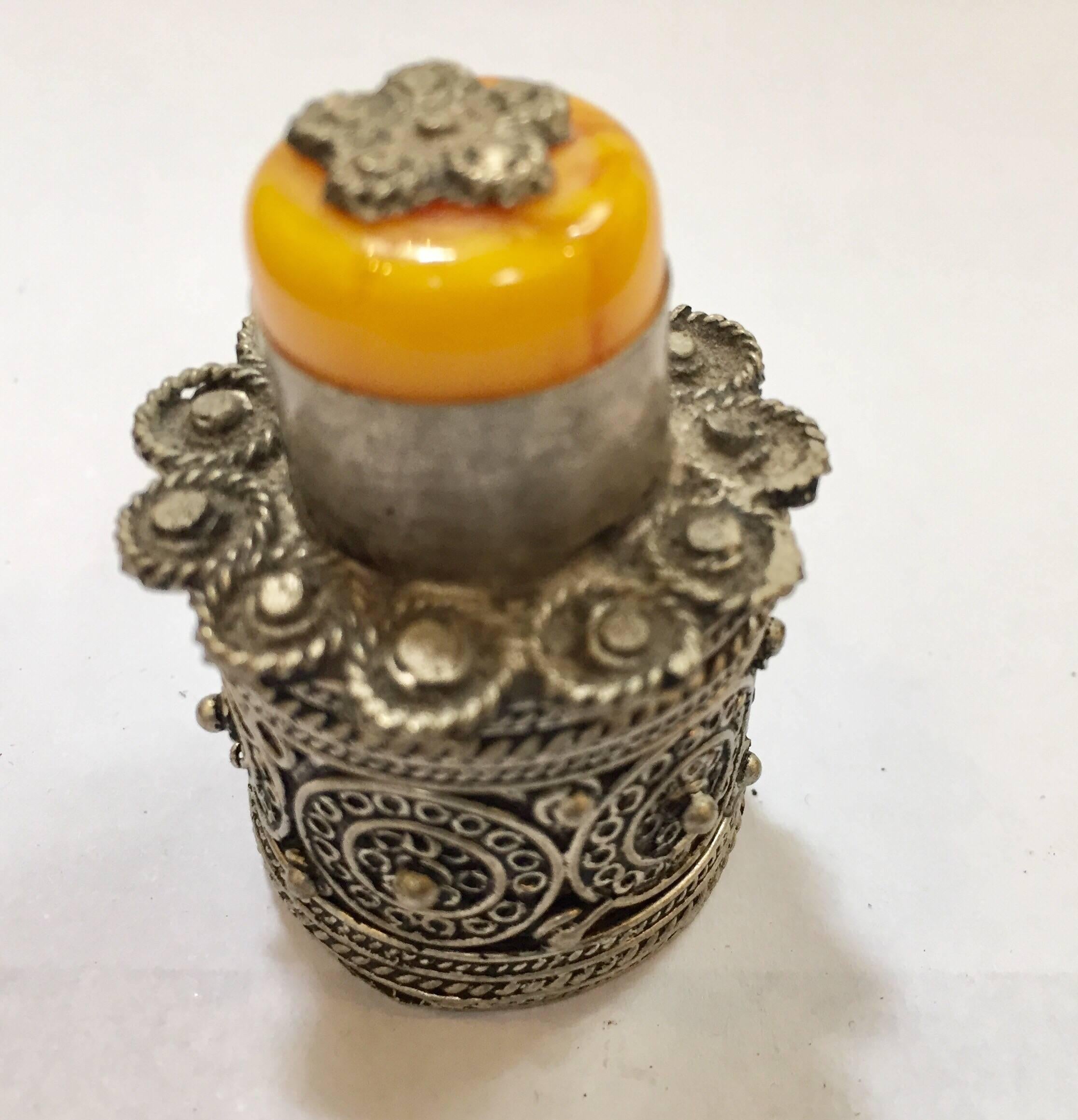 Silvered metal lidded box of a circular form for powder kohl eye liner.
Designed into two detached sections, finely handcrafted and decorated with scrollwork designs with a yellow amber stone on the top lid and lots of great detail.
Berber Kabyle
