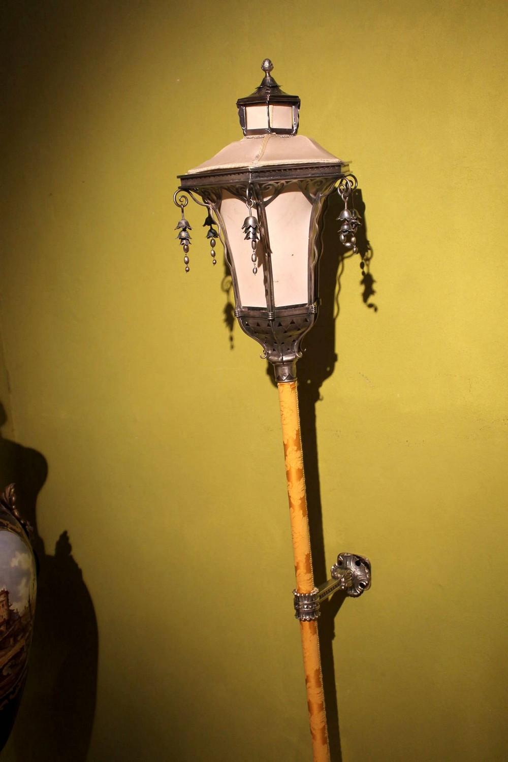 This Italian whismical silvered metal handcrafted wall-mounted lantern or sconce feature an open worked pagoda lidded lampshade embellished with scrolls and pendants in the form of flowers. The lower part of the lamp has pierced geometrical patterns