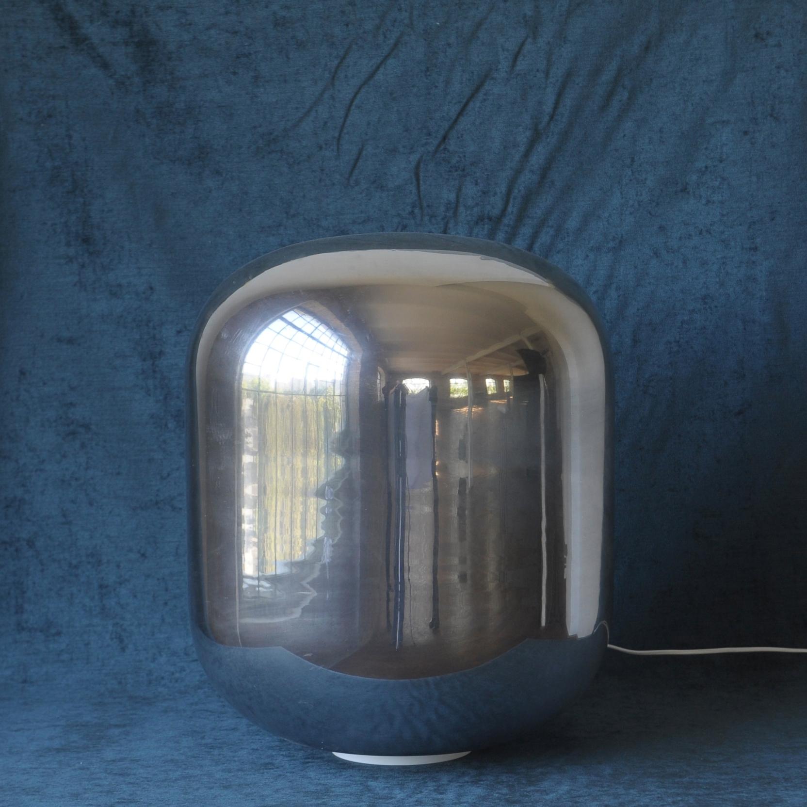 The lamp has a form of cocoon. Mirrored glass reflects when lamp is off.
The mirror effect ceases when light is on.