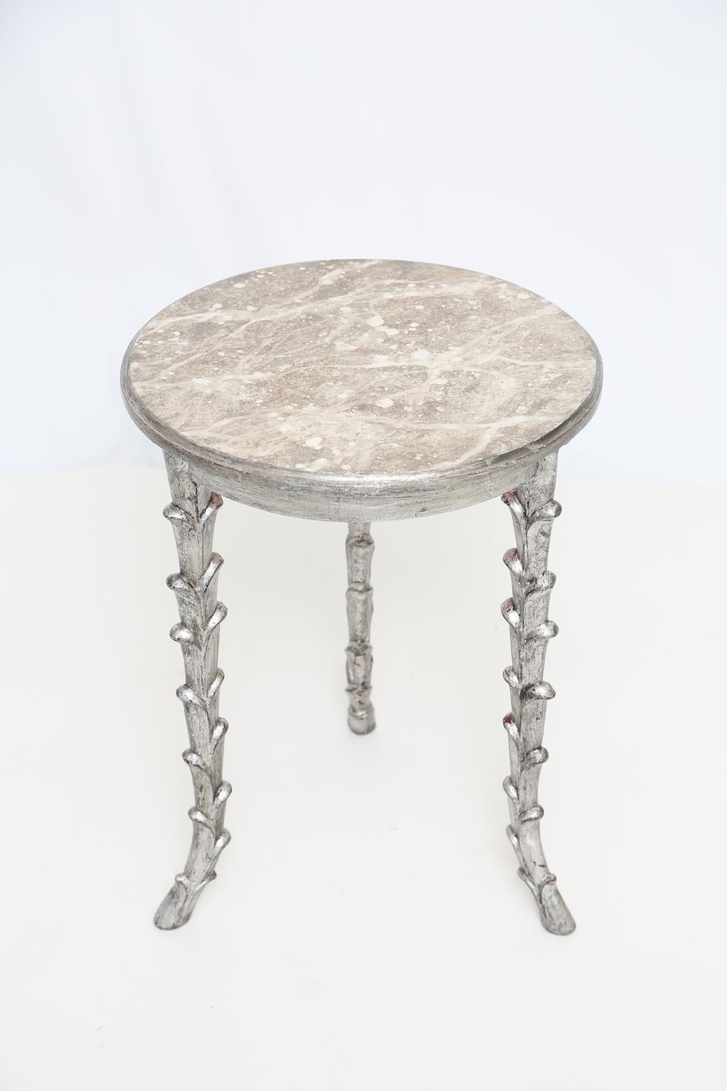 Accent table, having a round molded top of faux marble, raised on three, foliate-carved, silvergilt, splayed legs.

Stock ID: D2606.