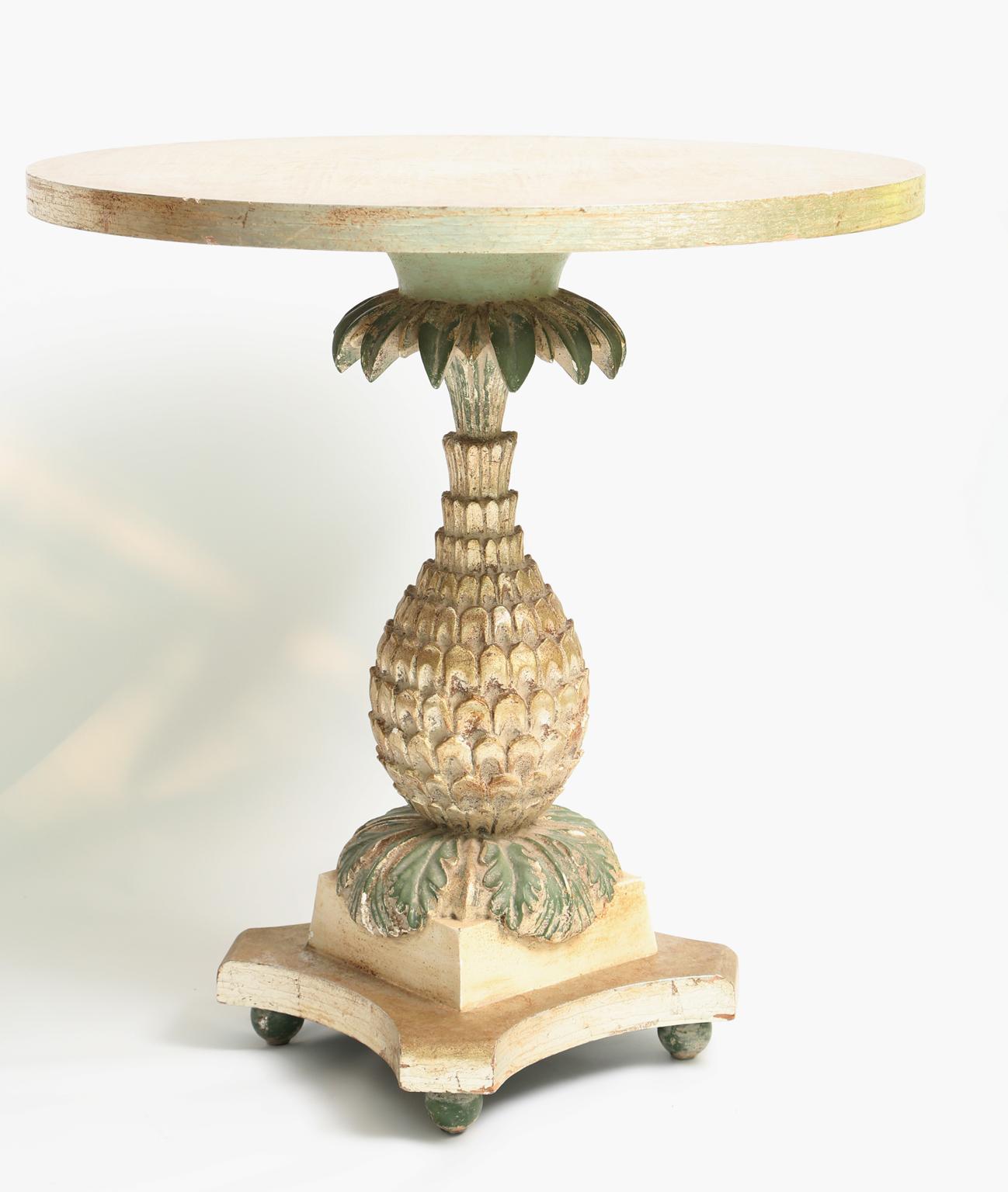 Table, having a silvergilt finish and painted finish showing natural wear, its round top raised on a pedestal base fashioned as a pineapple, on square plinth with concave sides, on bun feet. 

Stock ID: D2086.