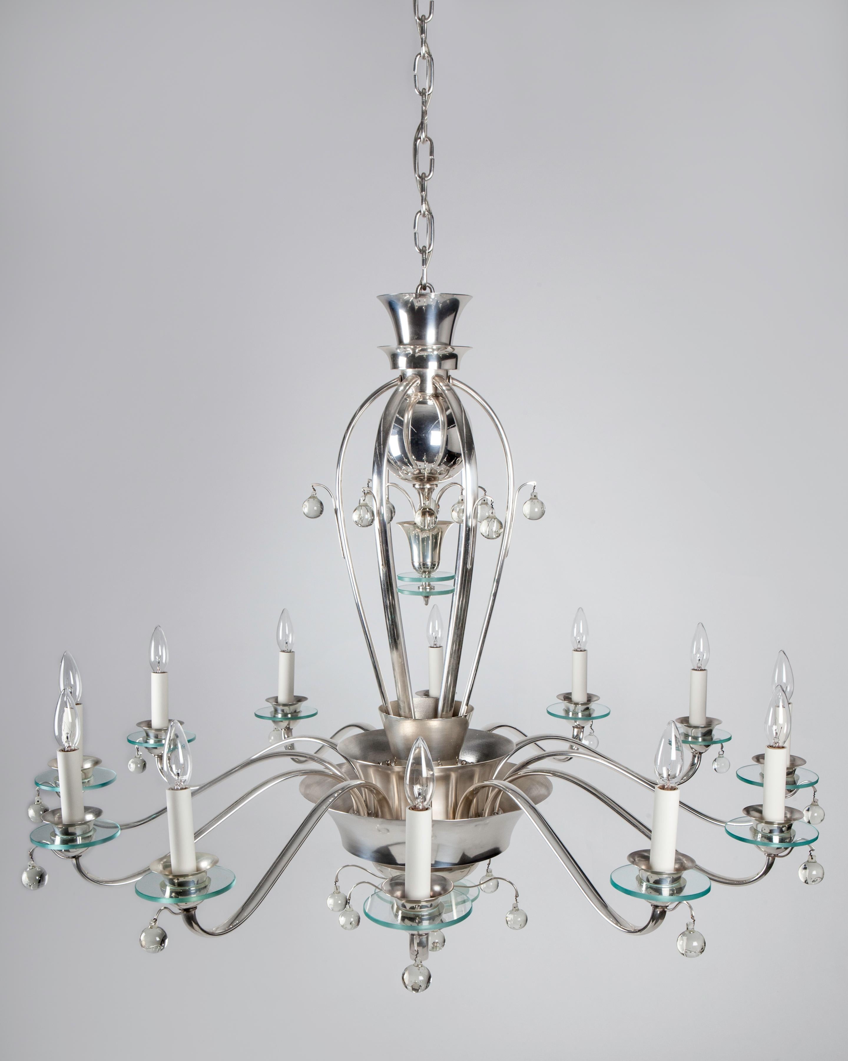 AHL4157
Circa 1930
A vintage Art Deco period silver plate chandelier with twelve arms radiating from a nested set of central bowls. Each arm terminates with a round plate glass bobeche and a clear crystal ball drop. Due to the antique nature of this