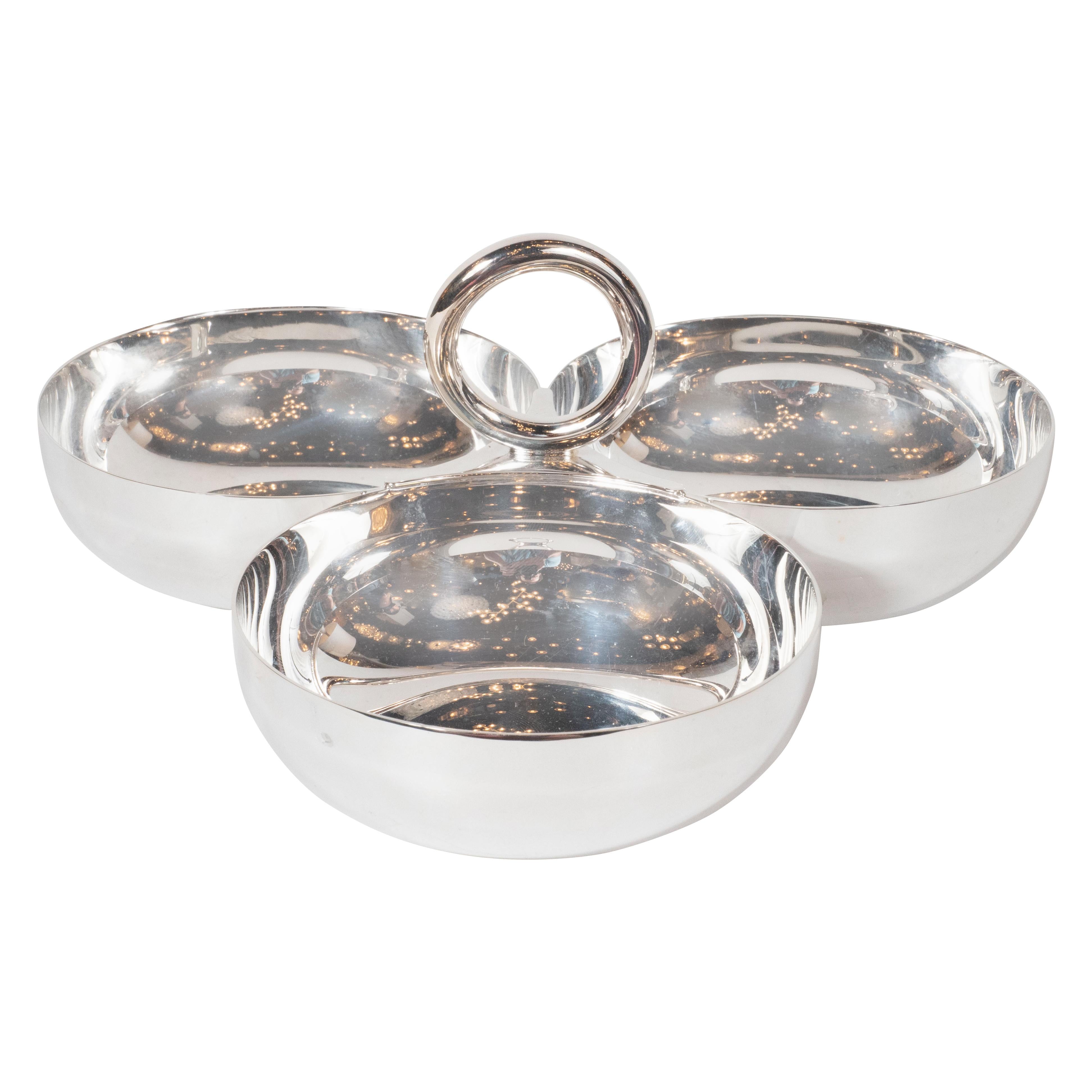 This elegant modernist silver plated hors d'ouevres dish- perfect for presenting olives, nuts or any other delicacy- was realized by Christofle in France. Part of their Vertigo Pattern series, the piece offers three conjoined circular dishes with