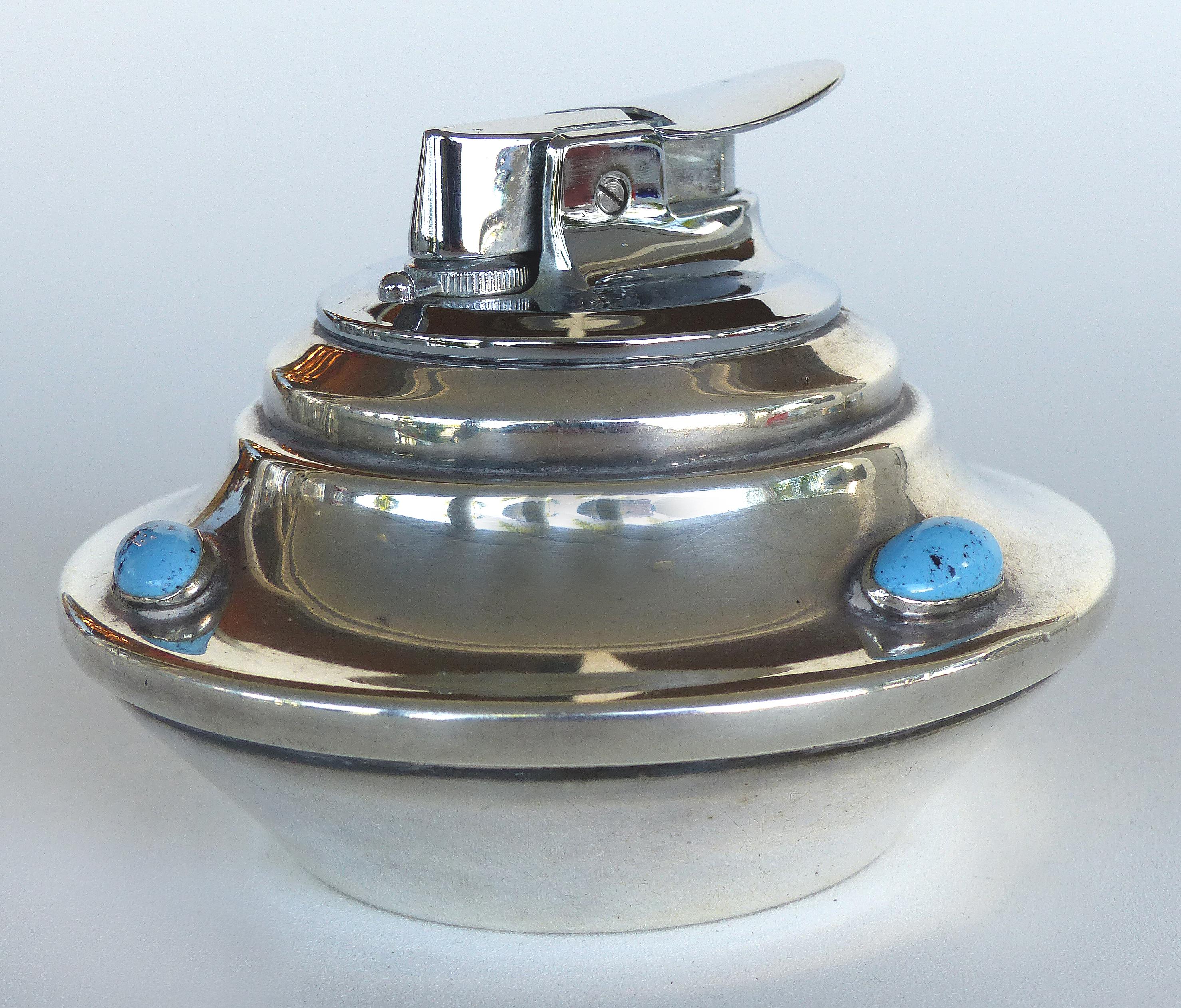 Offered for sale is a Mid-century Modern silverplate smoking set including a lighter and ashtray embellished by inset turquoise stones. The set has an Art Deco style form. Measurements given below are for the lighter; Ashtray measures 5