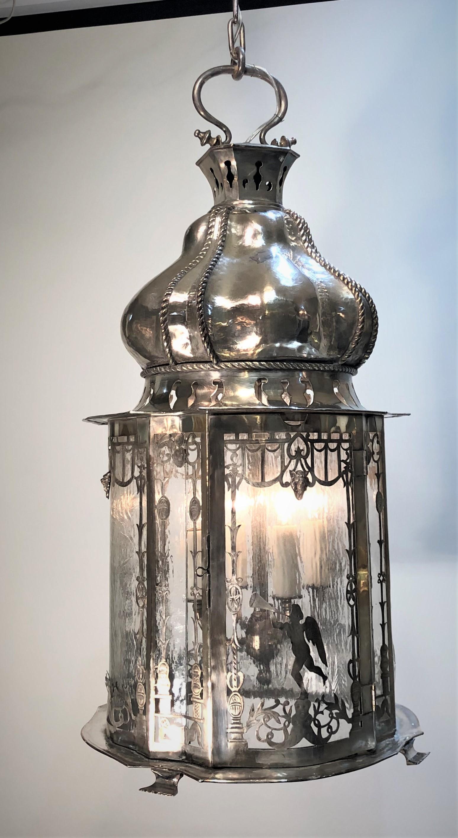 The Caldwell Lantern is silver-plated in an orientalist form of a tassel. This Whimsical Lantern is fashioned to resemble a hand tied corded knot coming down into a tassel. The tassel form body concave and convex with venetian glass panes framed