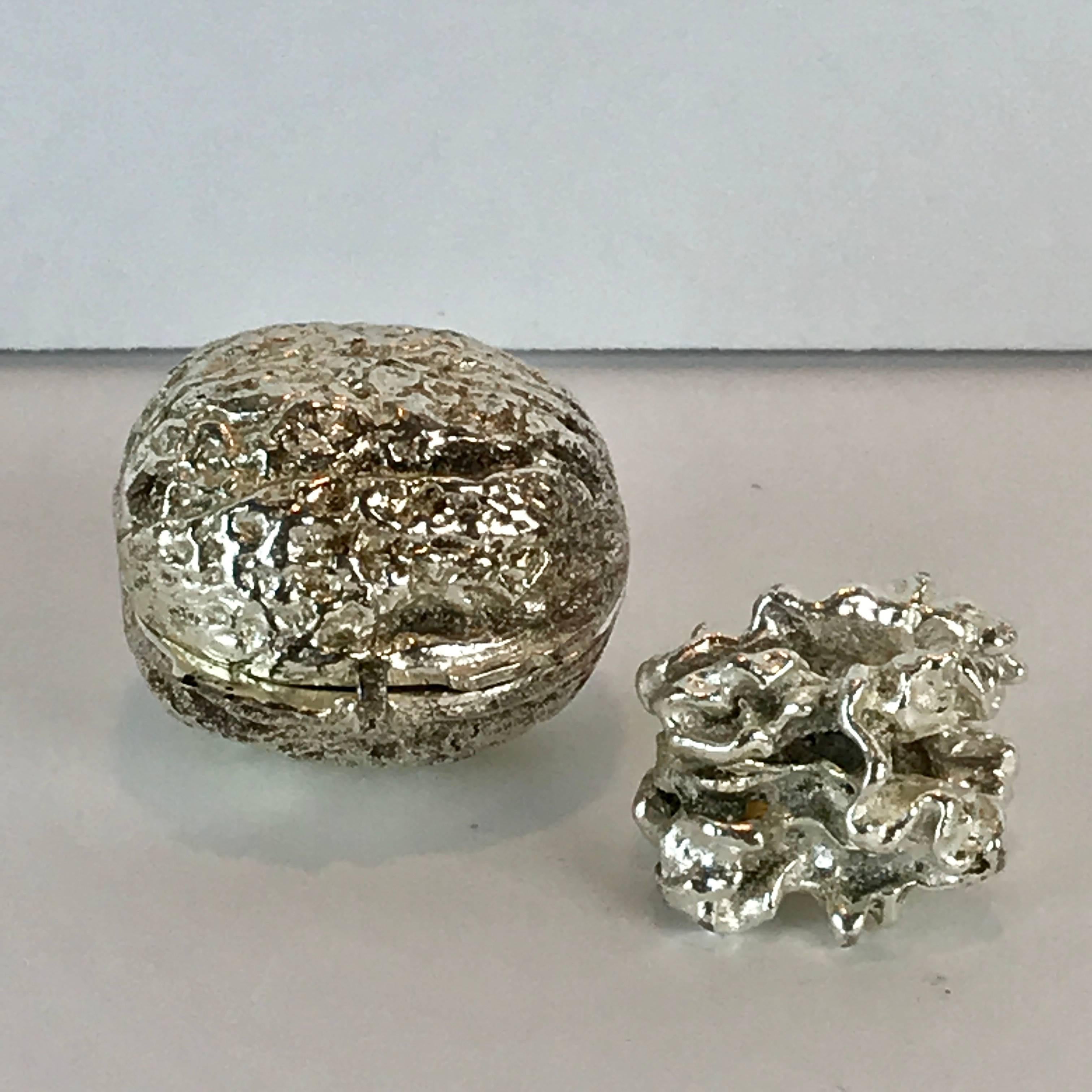 Silver plated bronze sculpture of a walnut. Lifesize, heavy, realistically cast in three pieces. Consisting of the hinged shell in two pieces and the kernel, unsigned
The shell measures 1.5