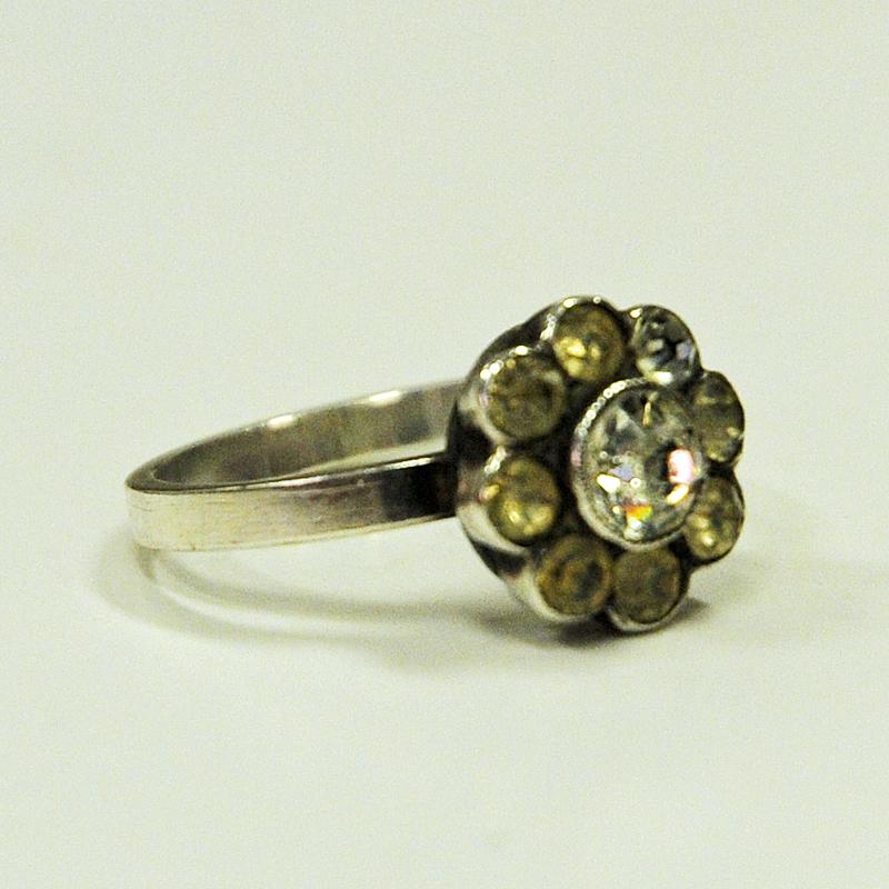 Nice and petite, cute and elegant! This vintage midcentury flower ring looks very good on your hand and has the most beautiful small stones gathered together as a flower. The outer stones are slightly light yellow and the bigger inner stones are
