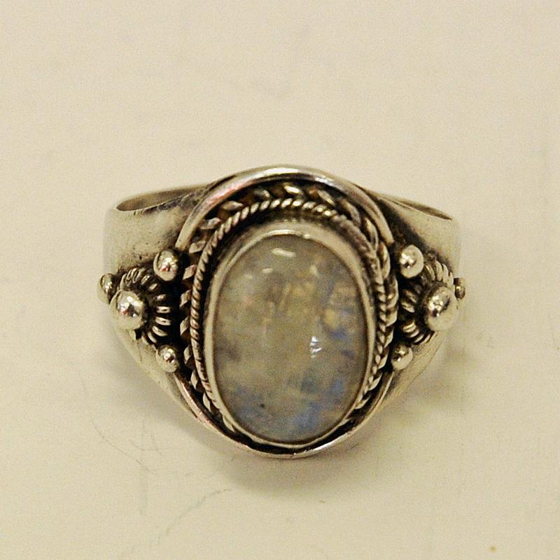 A decorative vintage ring with a shiny pearl stone surrounded by a decorated base of ornaments and patterns. Unknown designer and heritage but 925 silvermarked. Probably from circa 1940s. Inner diameter is 20 mm. Height of ring 28 mm. Length: 2 cm.