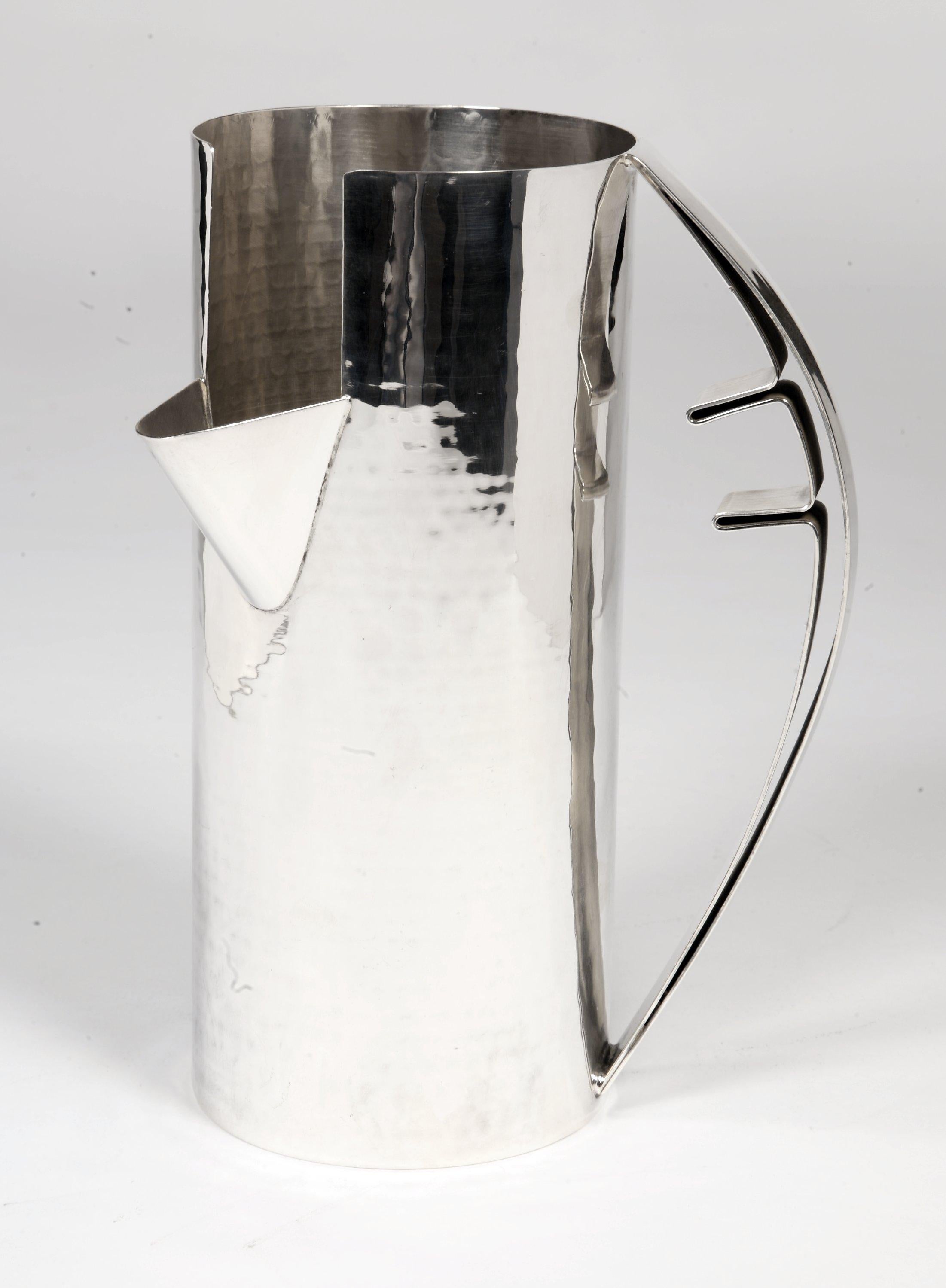 Krug aus gehämmertem, massivem Silber, bestehend aus einem kreisförmigen Henkel und einer Ausgusstülle, die sich auf 3/4 des Körpers befindet.

Abmessungen: 22 x 10cm
Gewicht: 584g
MATERIAL: Sterling Silber 925/°°
Punzierung: Verlagsstempel,