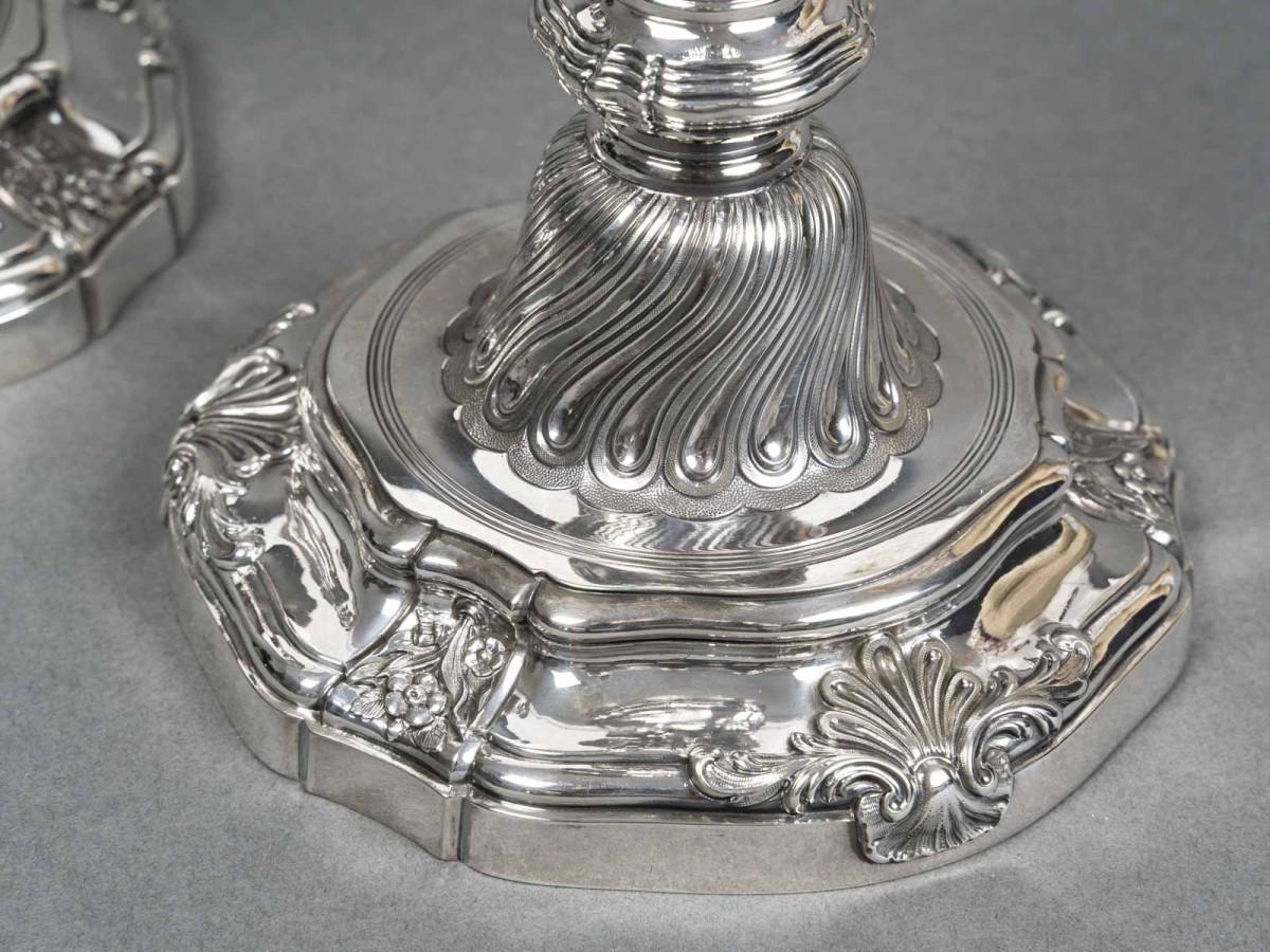 Ein Paar Kerzenhalter aus massivem Silber im Stil Louis XV. Der runde, geschwungene Sockel ist mit Muscheln verziert und wird von einem Stiel gekrönt, der unten mit Rillen, Akanthusblättern, Girlanden aus Palmettenblüten und verschlungenem Blattwerk