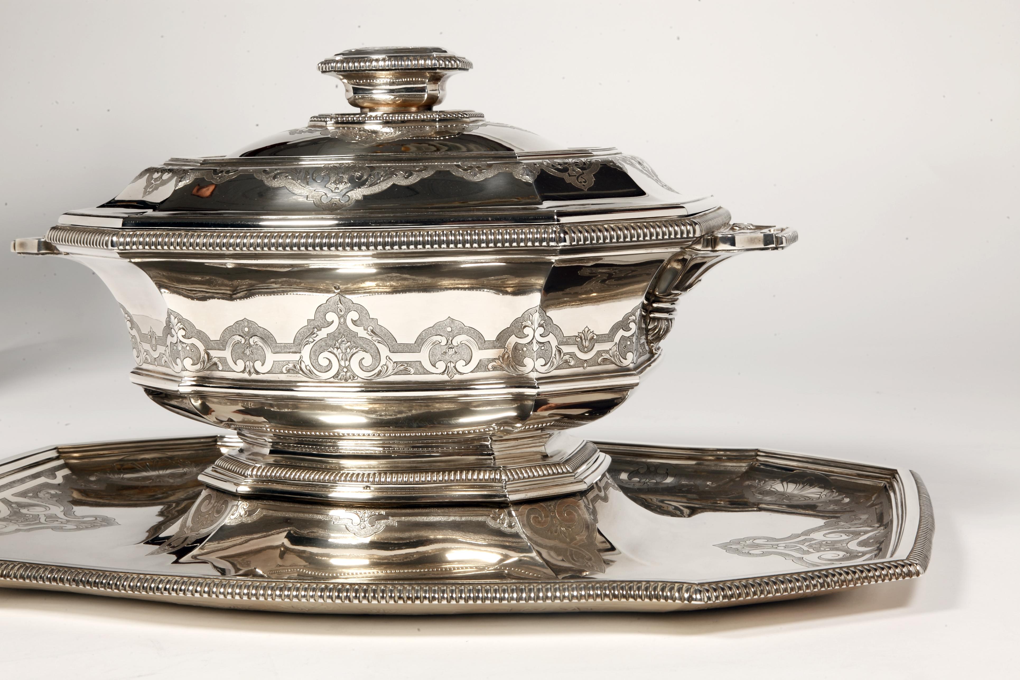 Centrotavola in argento massiccio composto da una grande zuppiera coperta montata su un piedistallo e racchiusa nel suo vassoio, di forma ottagonale, il set è delimitato da gadroons e inciso con un decoro Bérain in stile Regency.

Dimensioni: