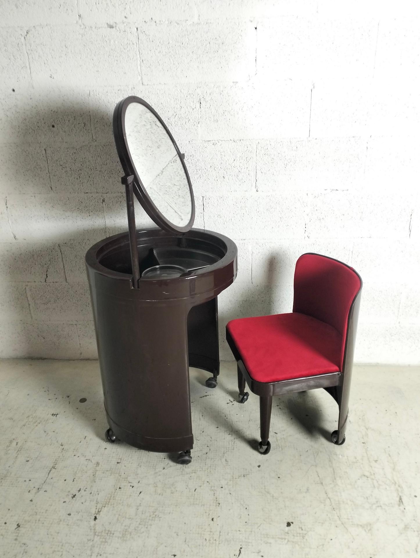 “Silvi” model dressing table, cylindrical body in plastic material containing an armchair with padded seat and backrest covered in fabric, a tilting mirror, wheels.
Good conditions. Wear consistent with age and use, some small and inevitable