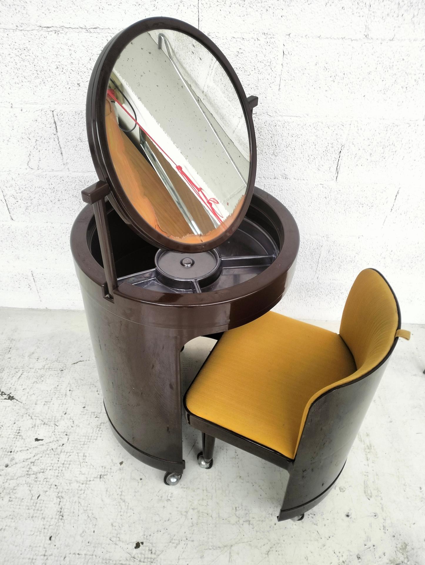 “Silvi” model dressing table, cylindrical body in plastic material containing an armchair with padded seat and backrest covered in fabric, a tilting mirror, wheels.

Good conditions. Wear consistent with age and use, some small and inevitable
