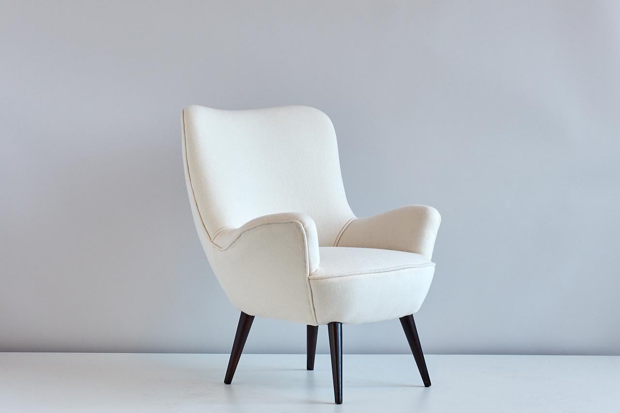 A rare armchair designed by Silvio Cavatorta in the 1950s. This comfortable chair is particularly striking due to its curvy and organically shaped form, complemented by the lacquered tapered legs. 
The chair has been fully reconditioned and newly