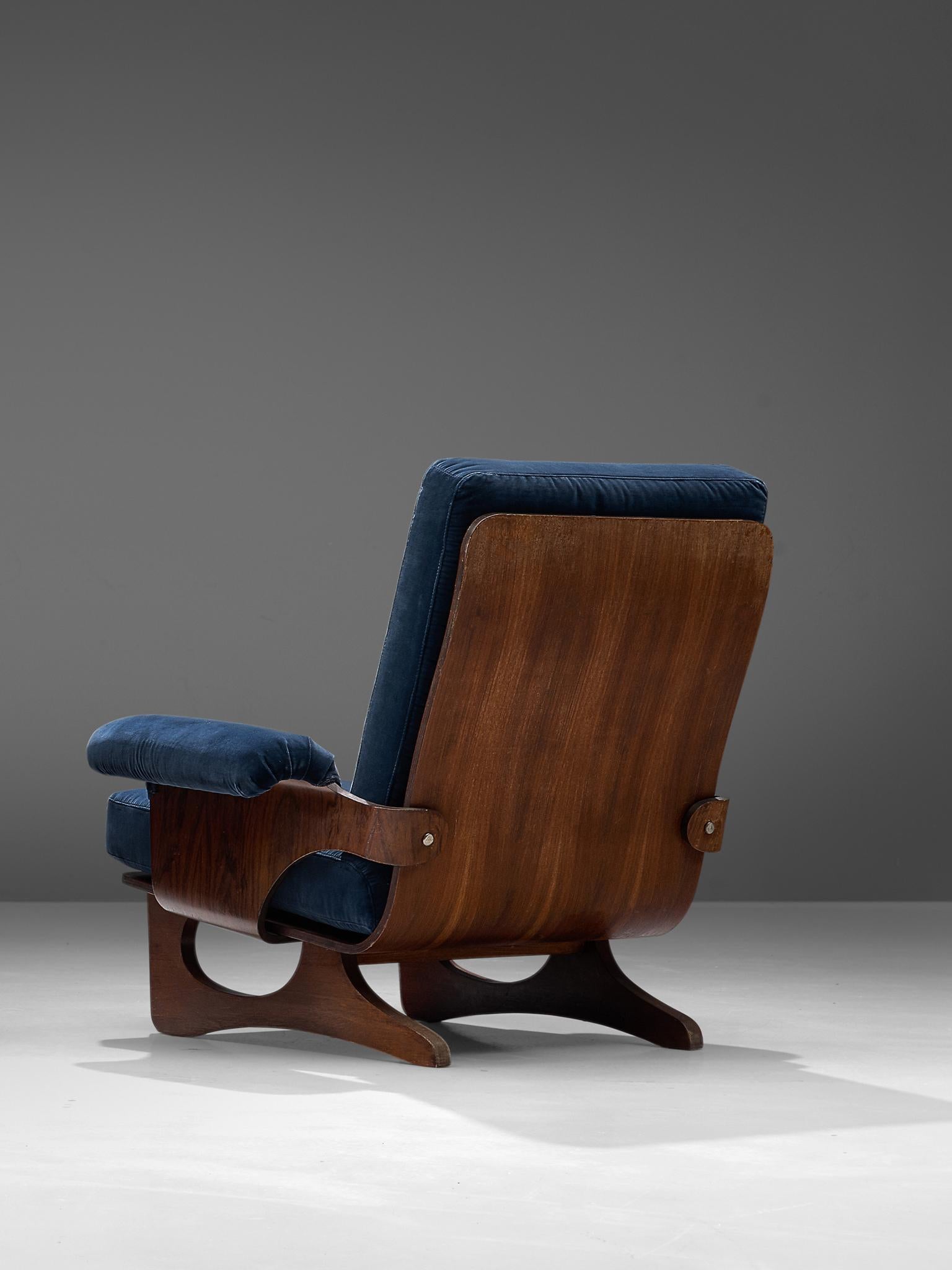 Silvio Cavatorta, lounge chair, blue velvet and teak, Italy, 1960s.

Armchair with beautiful bent teak frame and blue velvet upholstery. The seating and back are nicely curved to which the legs and armrests are attached. The armrests are finished