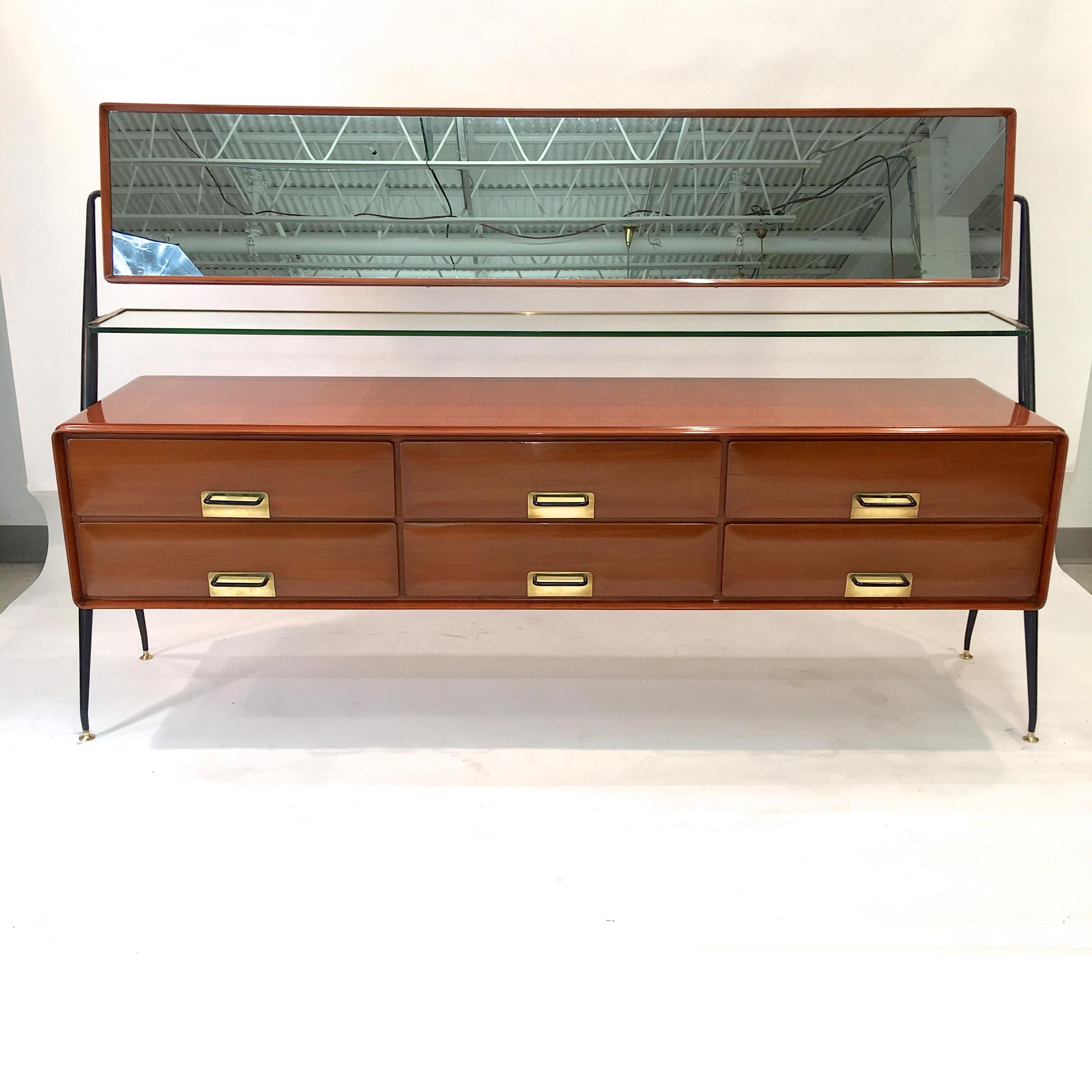 1950s Italian mahogany cabinet with six-drawers and a long horizontal tilting mahogany framed mirror over a brass framed crystal shelf, all mounted on distinctive tapered angular black steel supports each having two solid brass height adjustable