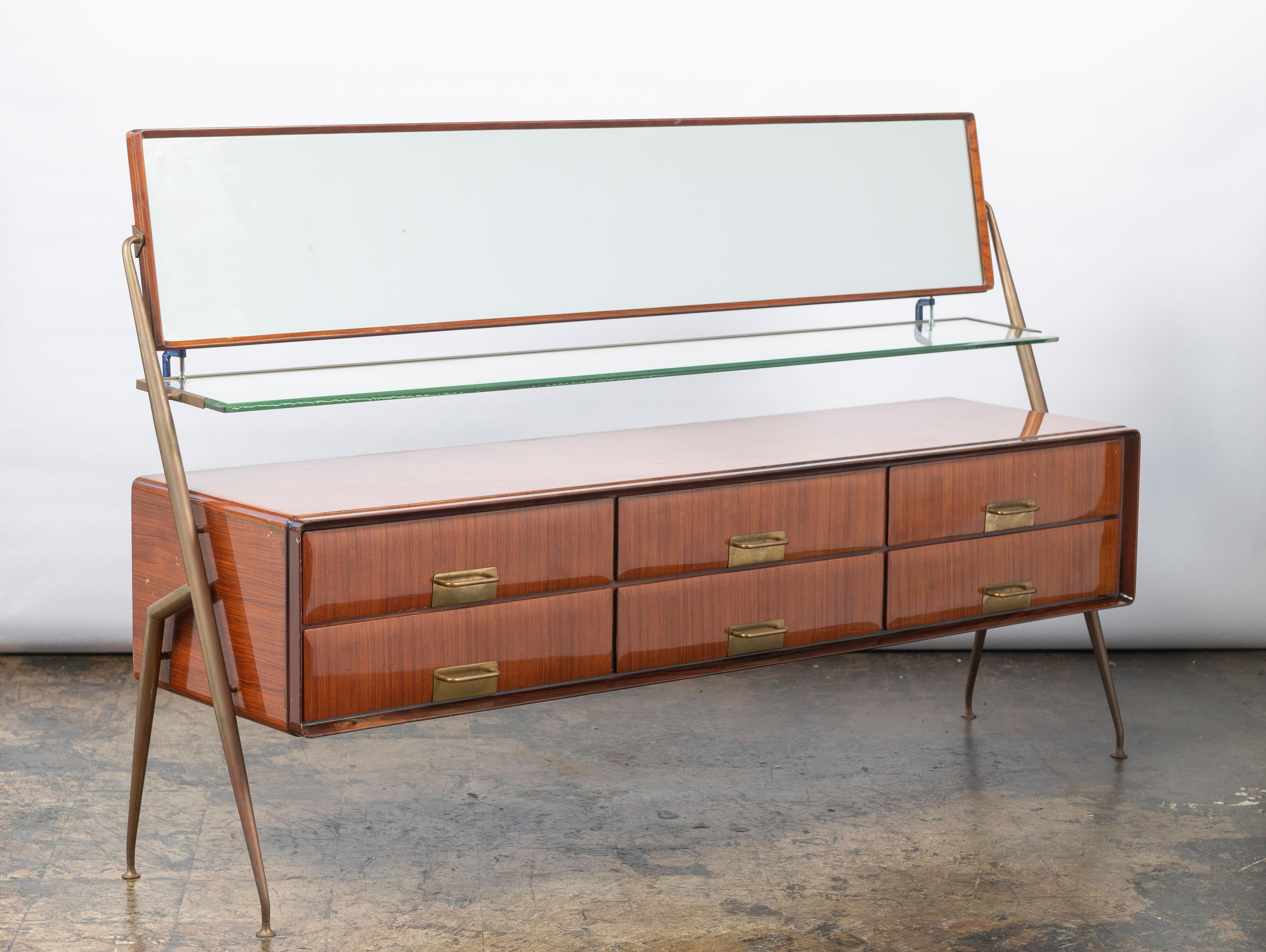 Stunning, sleek and modern, this dresser/credenza, made of polished rosewood veneer and brass fittings, is in good condition. Designed by renowned Italian designer, Silvio Cavatorta, the cabinet includes with six drawers, a glass shelf and a large,
