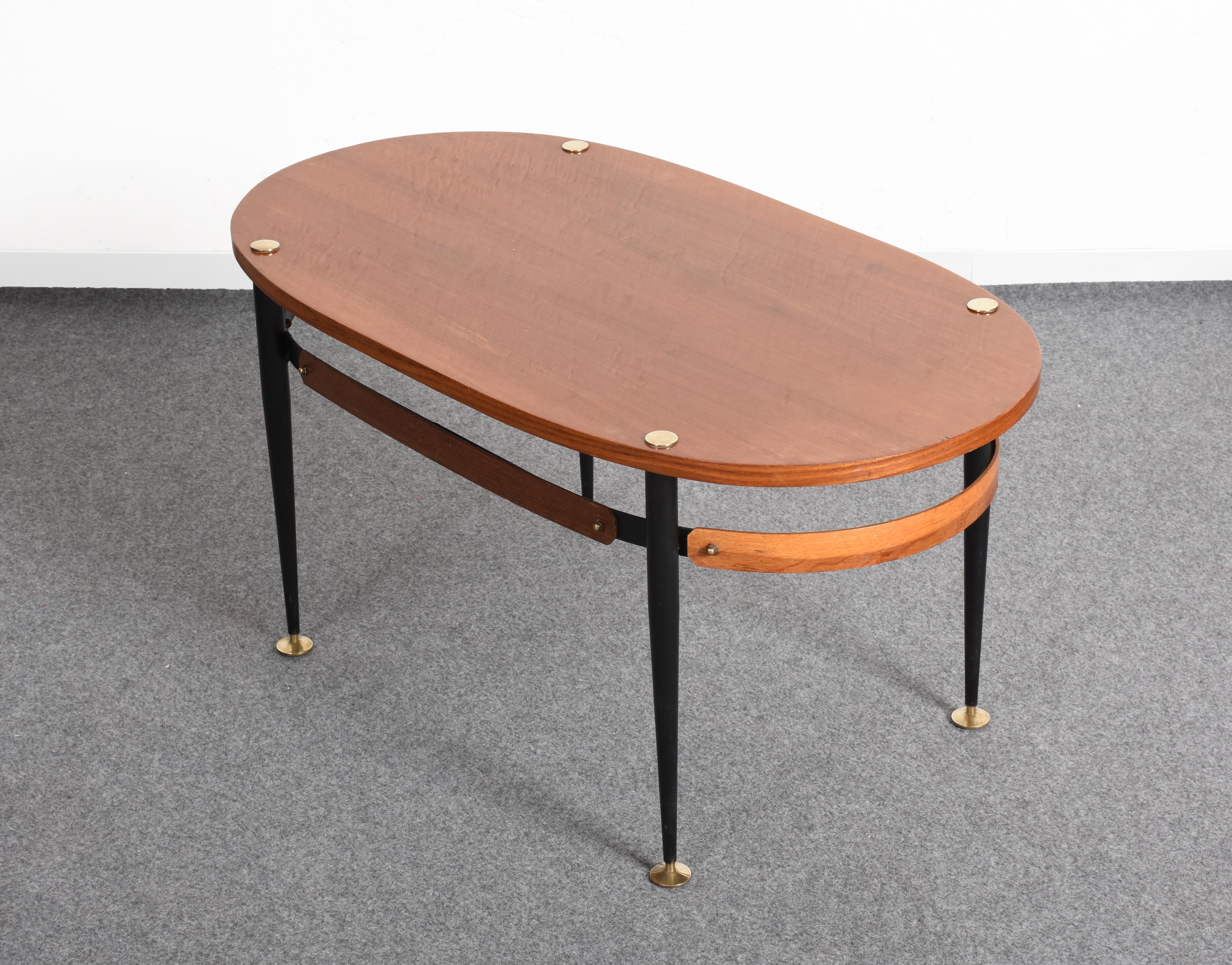 Beautiful Italian midcentury coffee table from the 1950s by Silvio Cavatorta.

It has a very elegant oval-shaped top mounted on painted iron legs. The feet and supports of the top are in solid brass. The lower band in Italian teak is astonishing