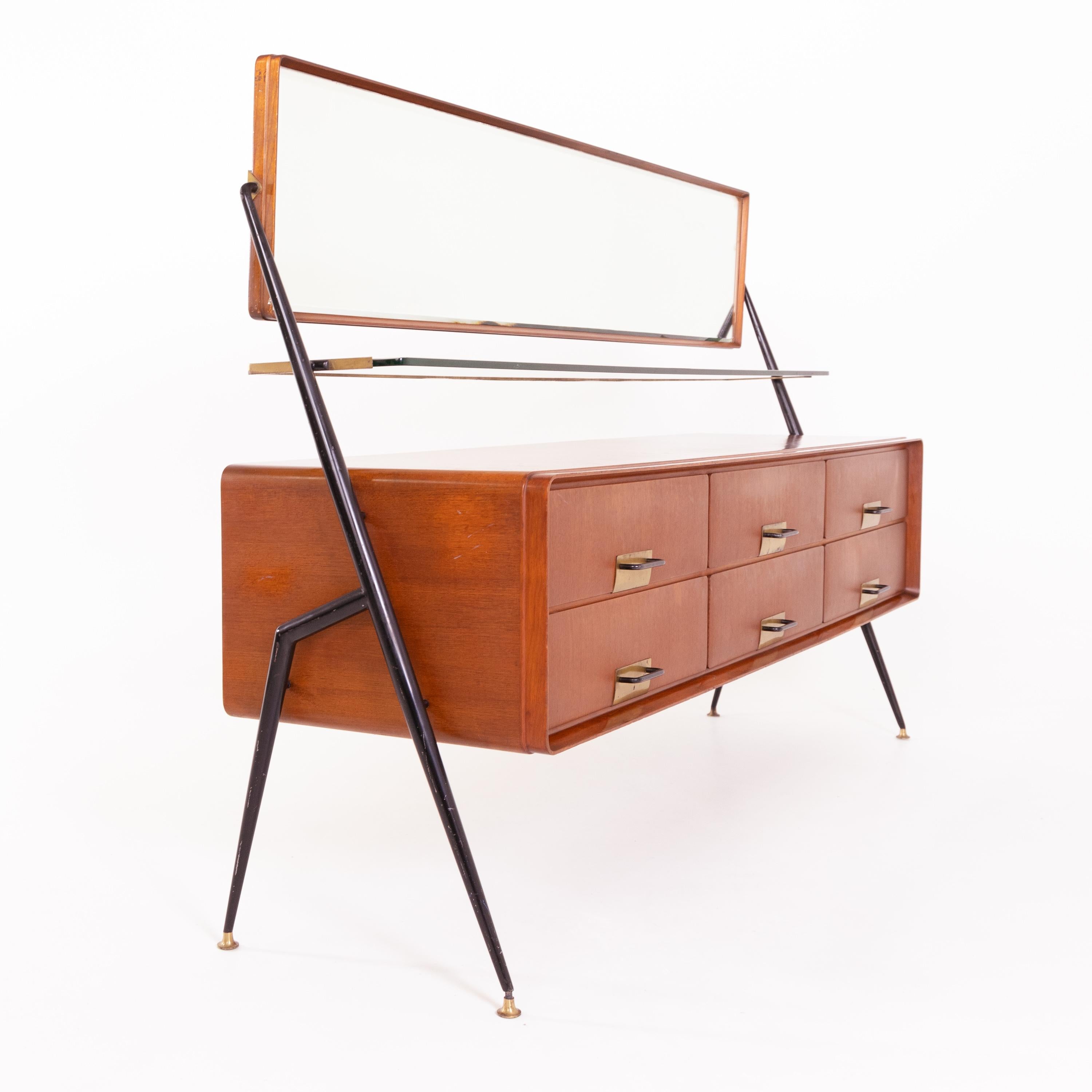Large sideboard designed by Silvio Cavatorta in the 1960s. The sideboard is standing on conical iron feet, with six drawers, a glass shelf, and tilting wide mirror on top.
  