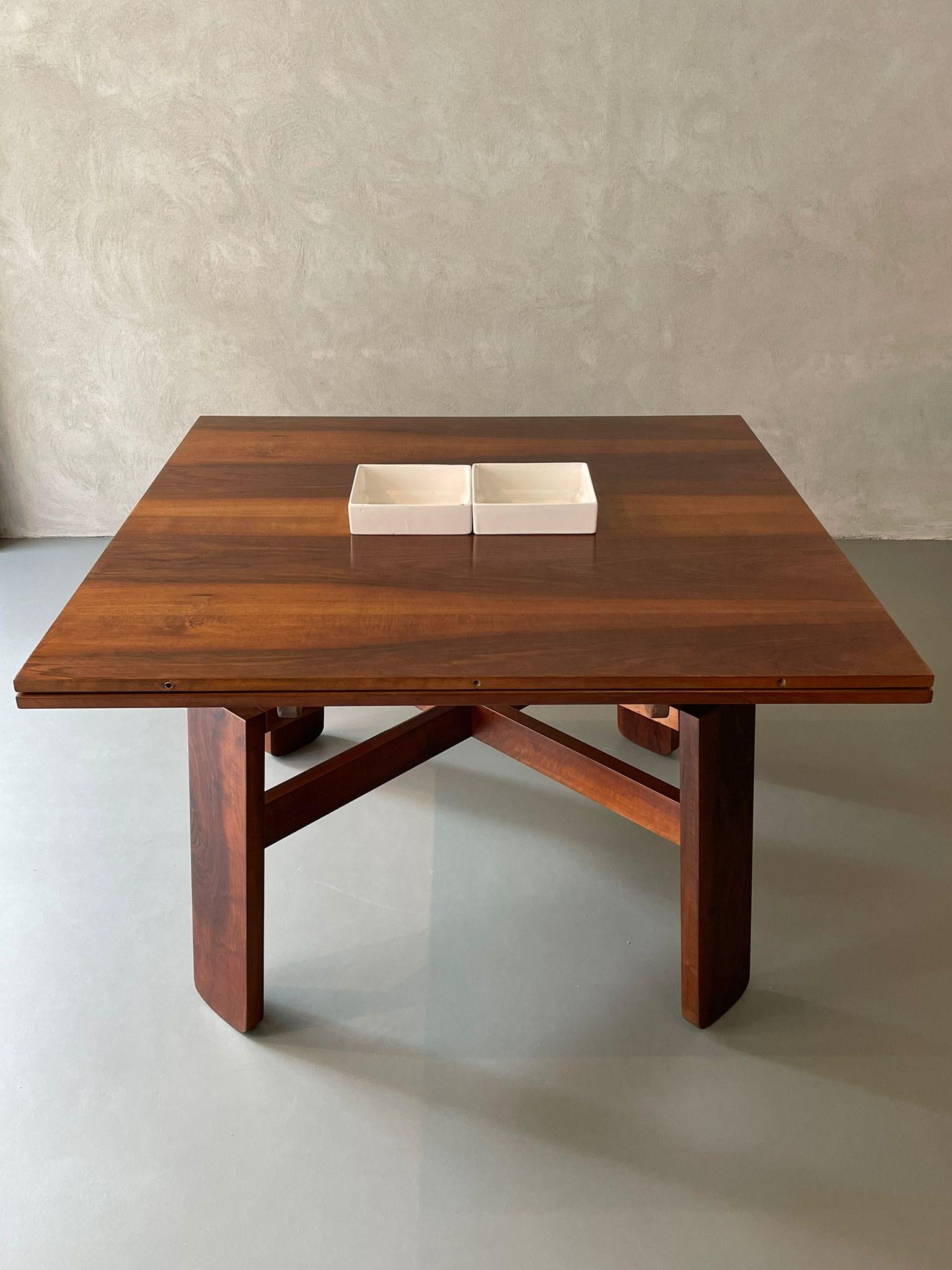 Square table designed by Silvio Coppola for Bernini, Italy, 1964.
The table is in walnut. The base has two wooden bars that cross each other. 
The table is extendable to take a rectangular shape:

Measures: 28.7 x 82.6 x 45.2 in
73 x 210 x 115