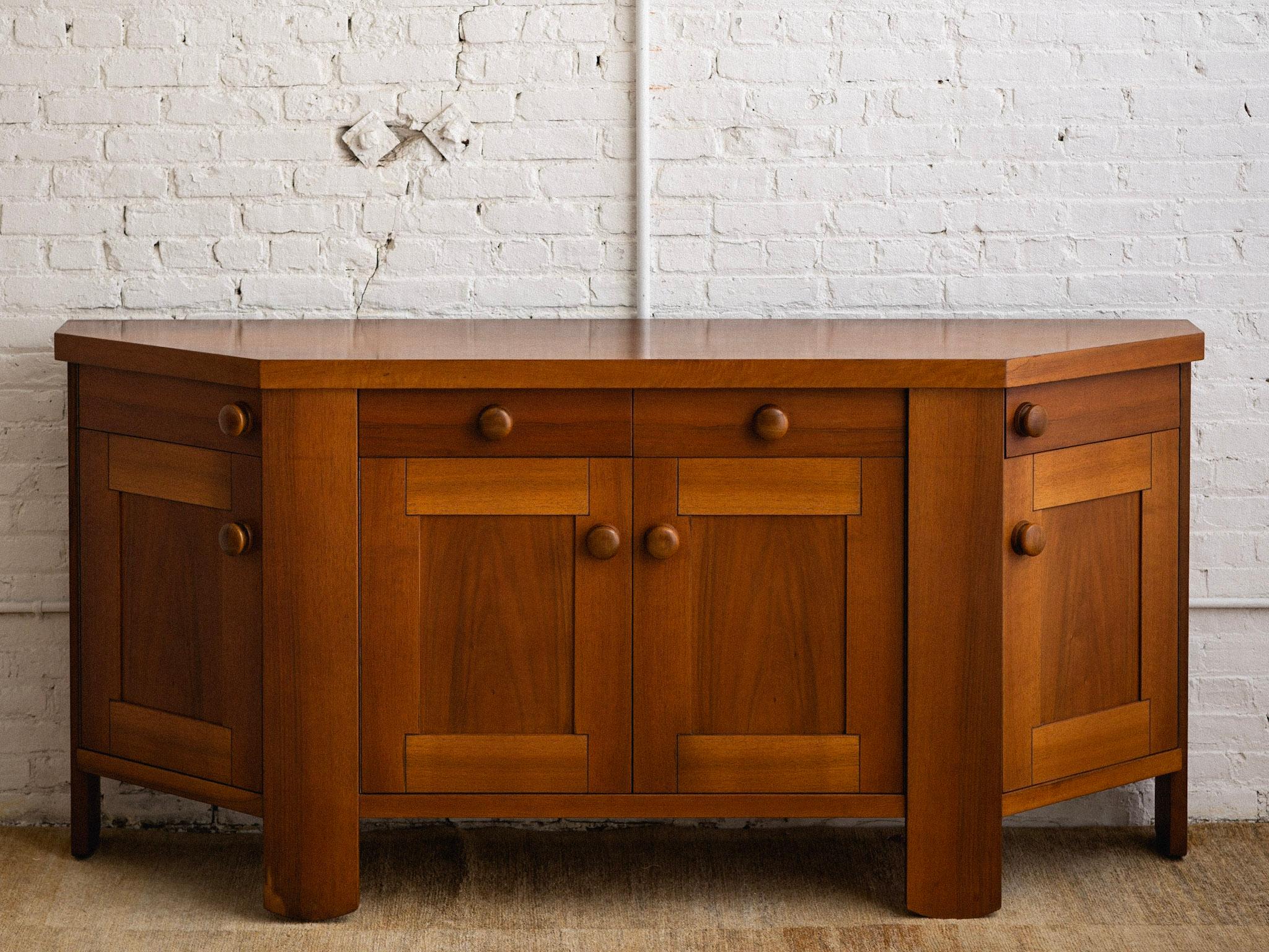 A midcentury Italian credenza / sideboard by Silvio Coppola for Bernini. Two center drawers with shelving below. Outer drawers open on a rounded track with cupboards below. Large wood pulls and a rich walnut finish. Sourced in Northern Italy.