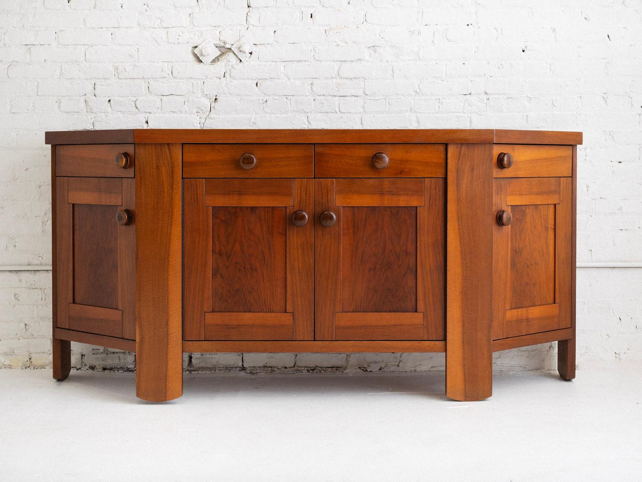A mid century Italian credenza / sideboard by Silvio Coppola for Bernini. Two center drawers with shelving below. Outer drawers open on a rounded track with cupboards below. Large wood pulls and a rich walnut finish. Sourced in Northern
