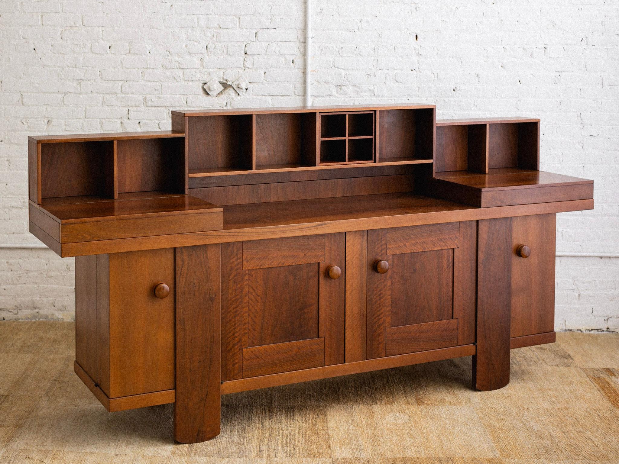 A midcentury Italian sideboard by Silvio Coppola for Bernini. Upper cupboards open to reveal removable trays. Lower cabinets feature adjustable shelves. Large wood pulls and a rich walnut finish. Sourced in Northern Italy. Upper shelving removes for