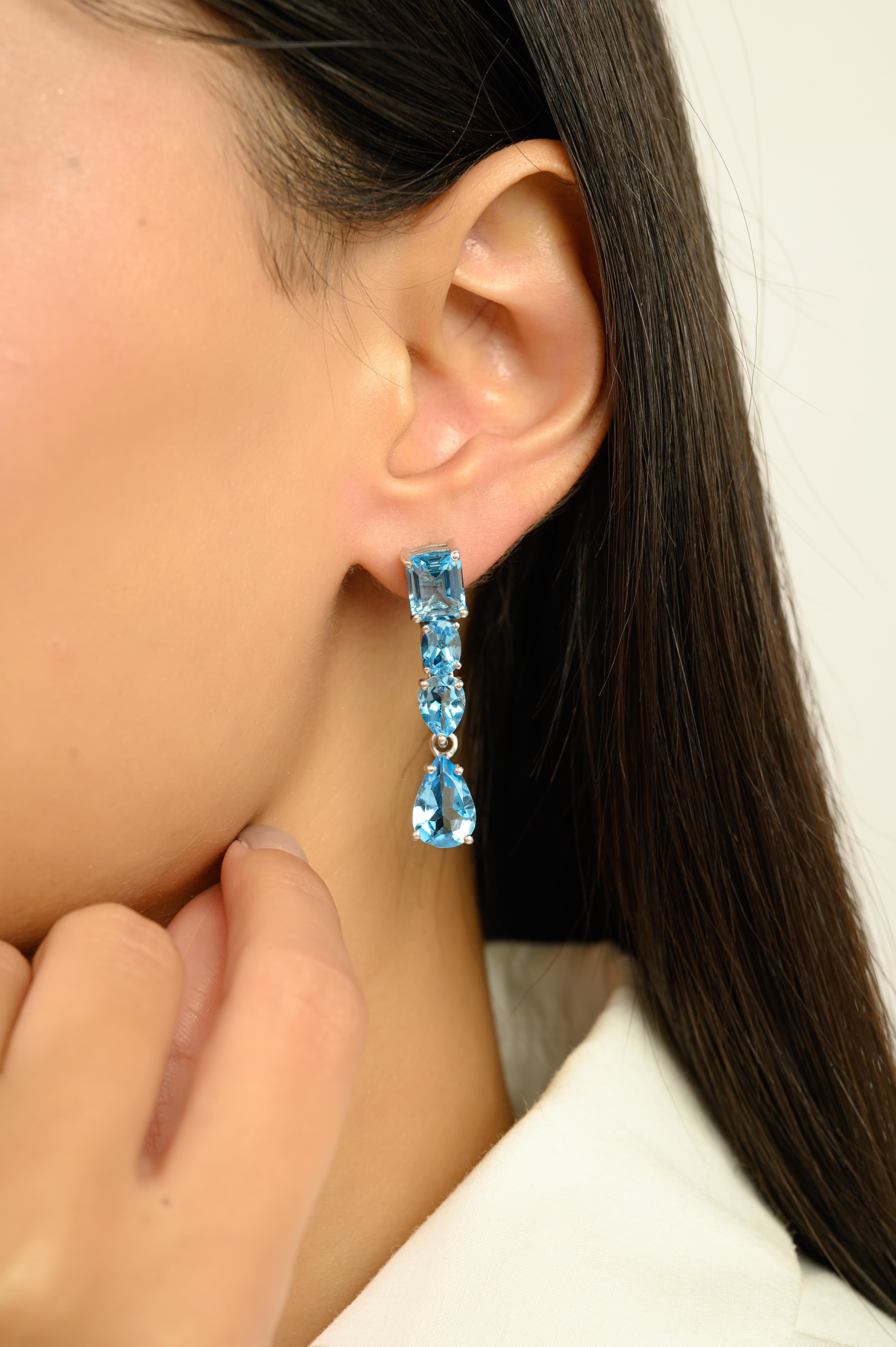 Estos elegantes pendientes colgantes están hechos a mano en auténtica plata de ley 925 y adornados con gemas naturales de topacio azul. Cada pendiente presenta una impresionante composición de ocho piedras de forma mixta, talla esmeralda, oval y