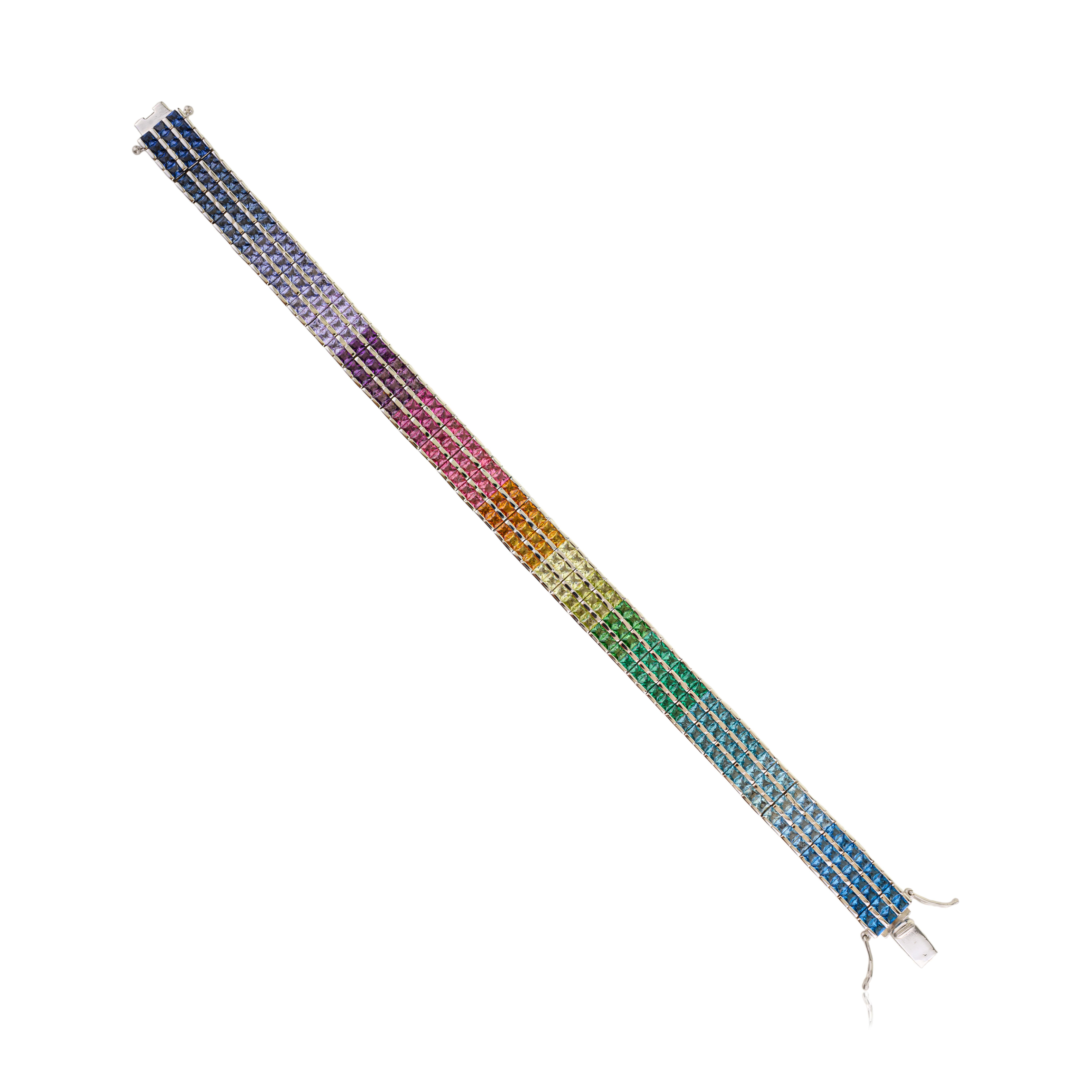 This elegant solid 925 sterling silver three-row tennis bracelet showcases vibrant, square cut cubic zirconia in a rainbow of hues. Each stone measures 2 x 2 mm and is precisely set in neat rows, creating a colorful, eye catching sparkle. The