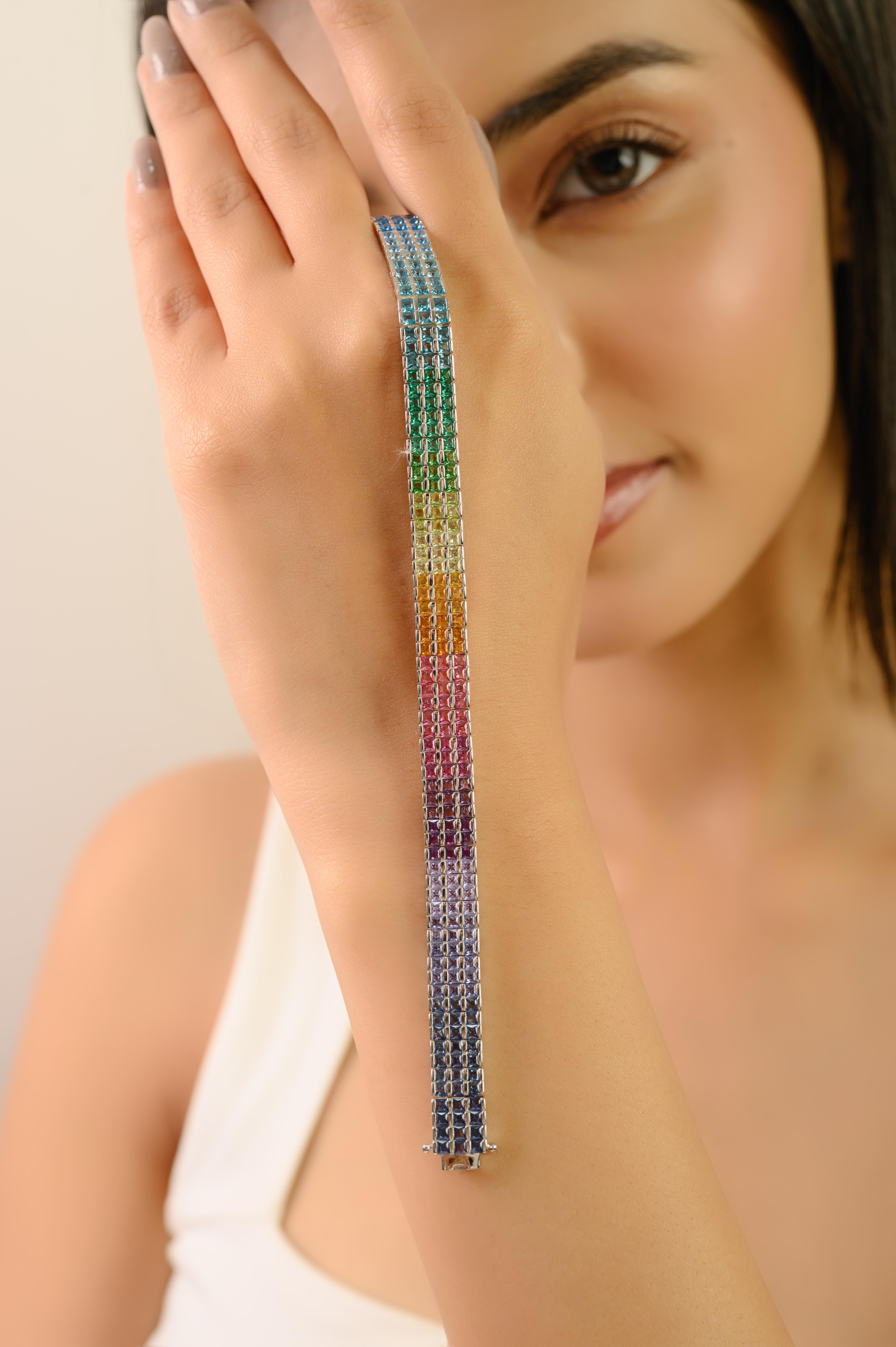 Esta elegante pulsera tenis de tres filas de plata de ley 925 maciza exhibe vibrantes circonitas de corte cuadrado en un arco iris de tonalidades. Cada piedra mide 2 x 2 mm y está engastada con precisión en filas ordenadas, creando un destello
