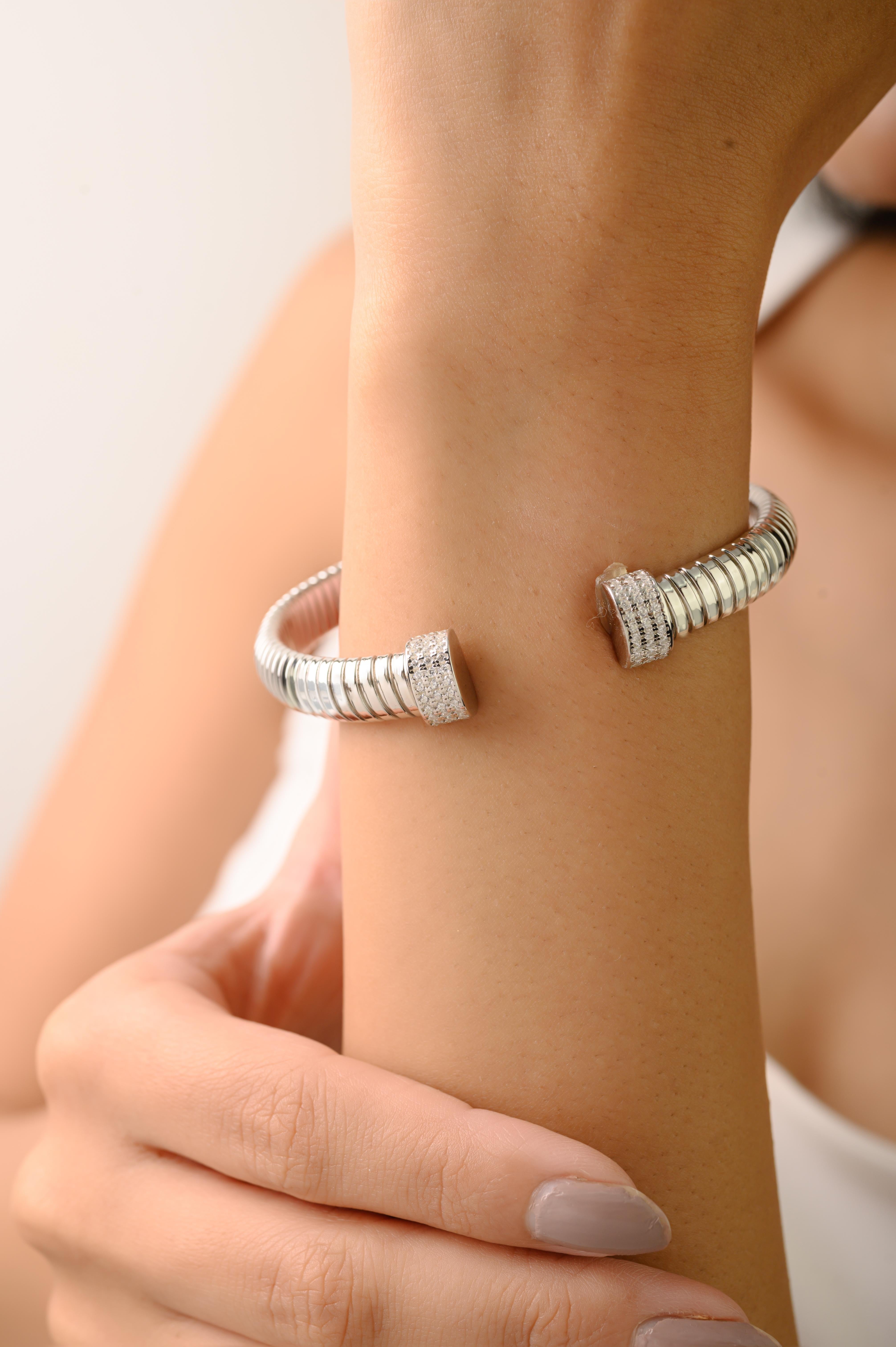 Questo elegante braccialetto in argento sterling 925 presenta un design a spirale elegante e contemporaneo che offre flessibilità e comfort duraturi. Ogni estremità è graziosamente sormontata da cupole rifinite, incastonate con brillanti pietre di