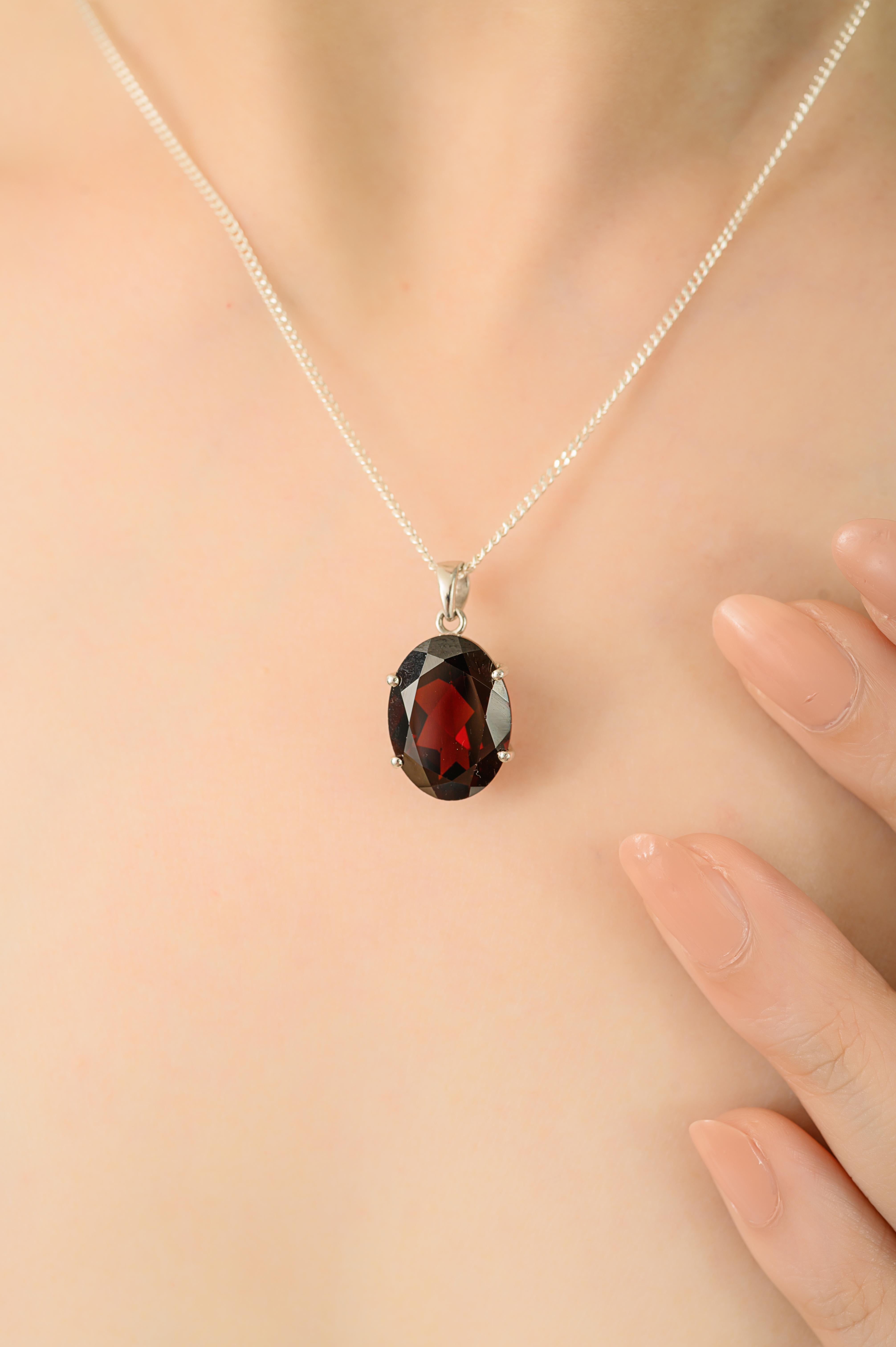 This elegant pendant is crafted in 925 sterling silver and features a natural oval shaped garnet. The garnet weighs 9 carats, measures 15x11 mm and is securely set in prongs and pendant is 0.85 inches long and weighs 3.35 grams. With its rich red
