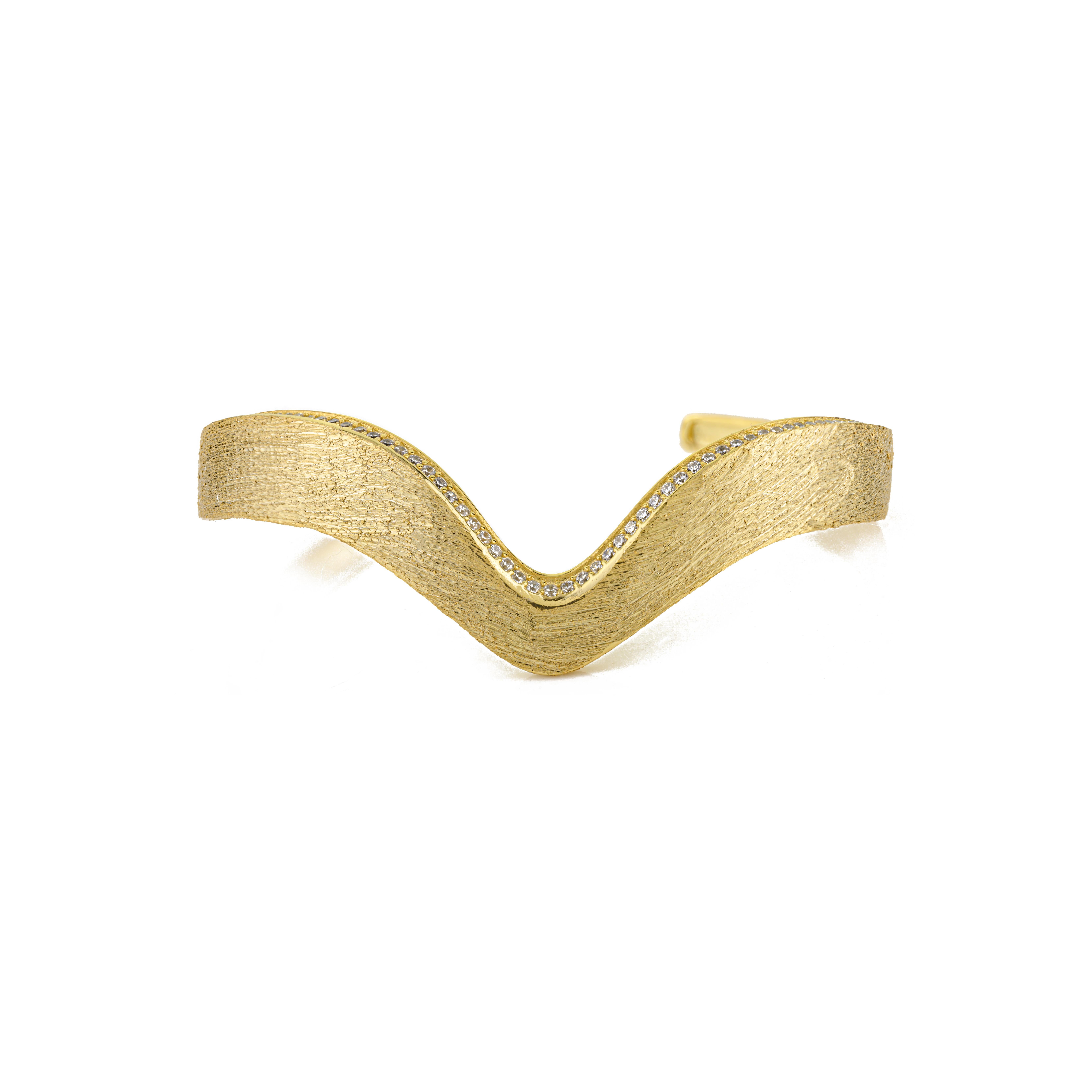 Ce bracelet en argent sterling 925 fabriqué à la main présente un élégant design inspiré des vagues, fini par une luxueuse texture mate de couleur or. Orné de délicates pierres en zircon cubique de 1 mm qui scintillent subtilement le long de la