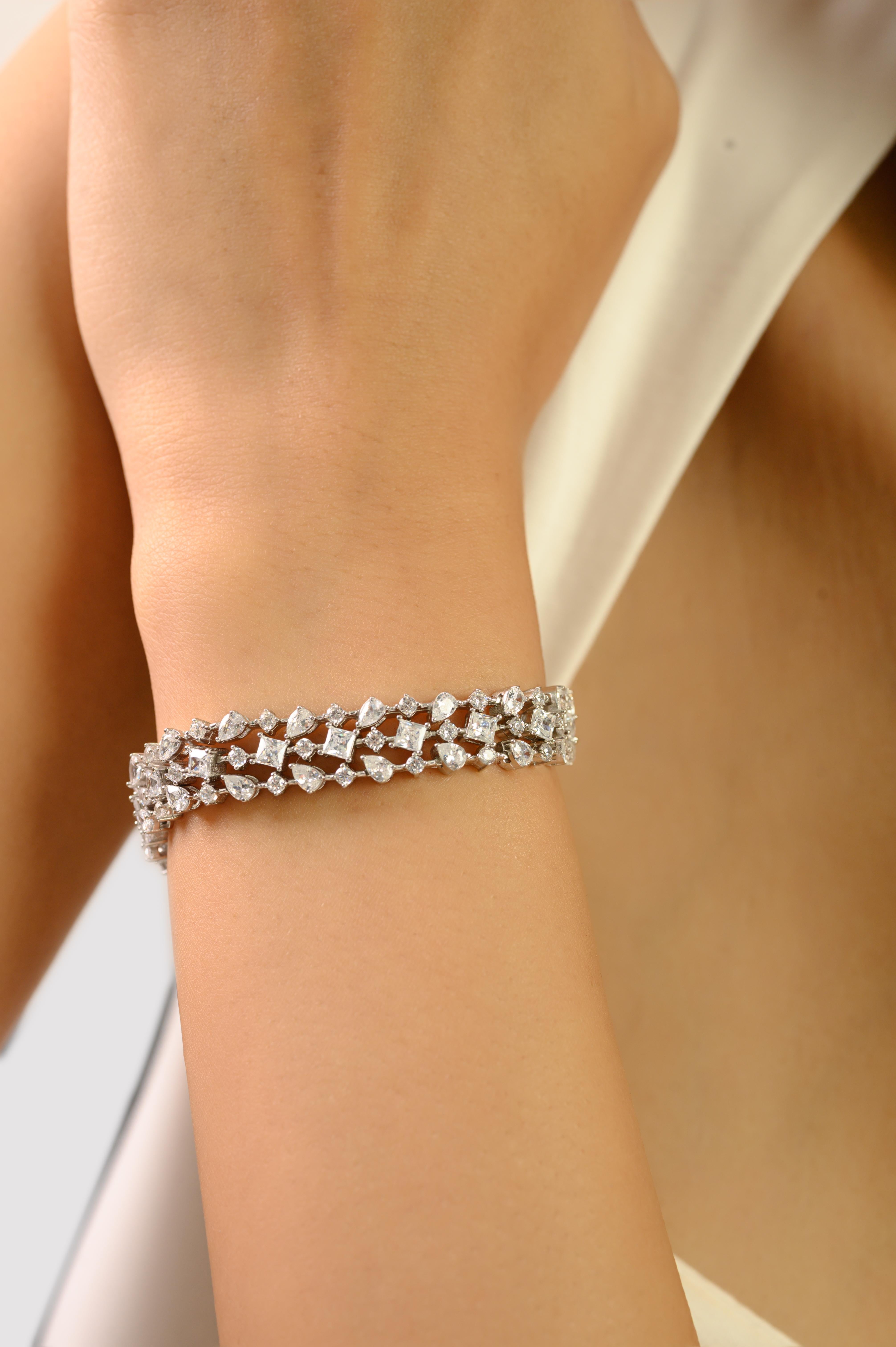 Esta impresionante pulsera tenis de plata de ley 925 exhibe una lujosa triple hilera de brillantes circonitas cúbicas blancas de talla múltiple, cada una delicadamente engastada para maximizar el brillo. El brillo continuo crea una línea elegante