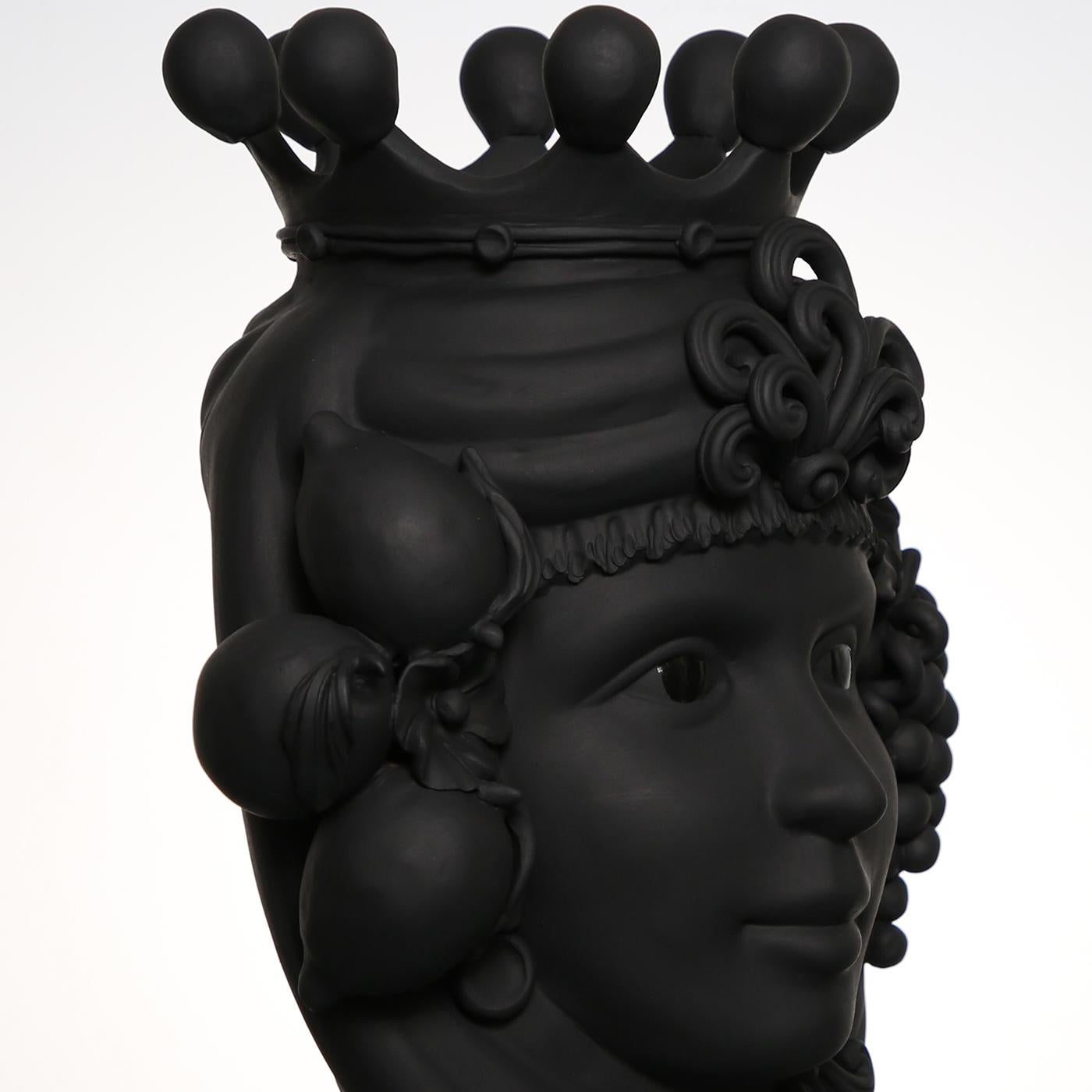 Ce vase anthropomorphe est entièrement réalisé à la main et peint dans une teinte monochrome noire et mate, riche en pigments naturels et en liants résineux qui donnent une profondeur de couleur intense. Seuls les yeux sont glacés afin qu'ils