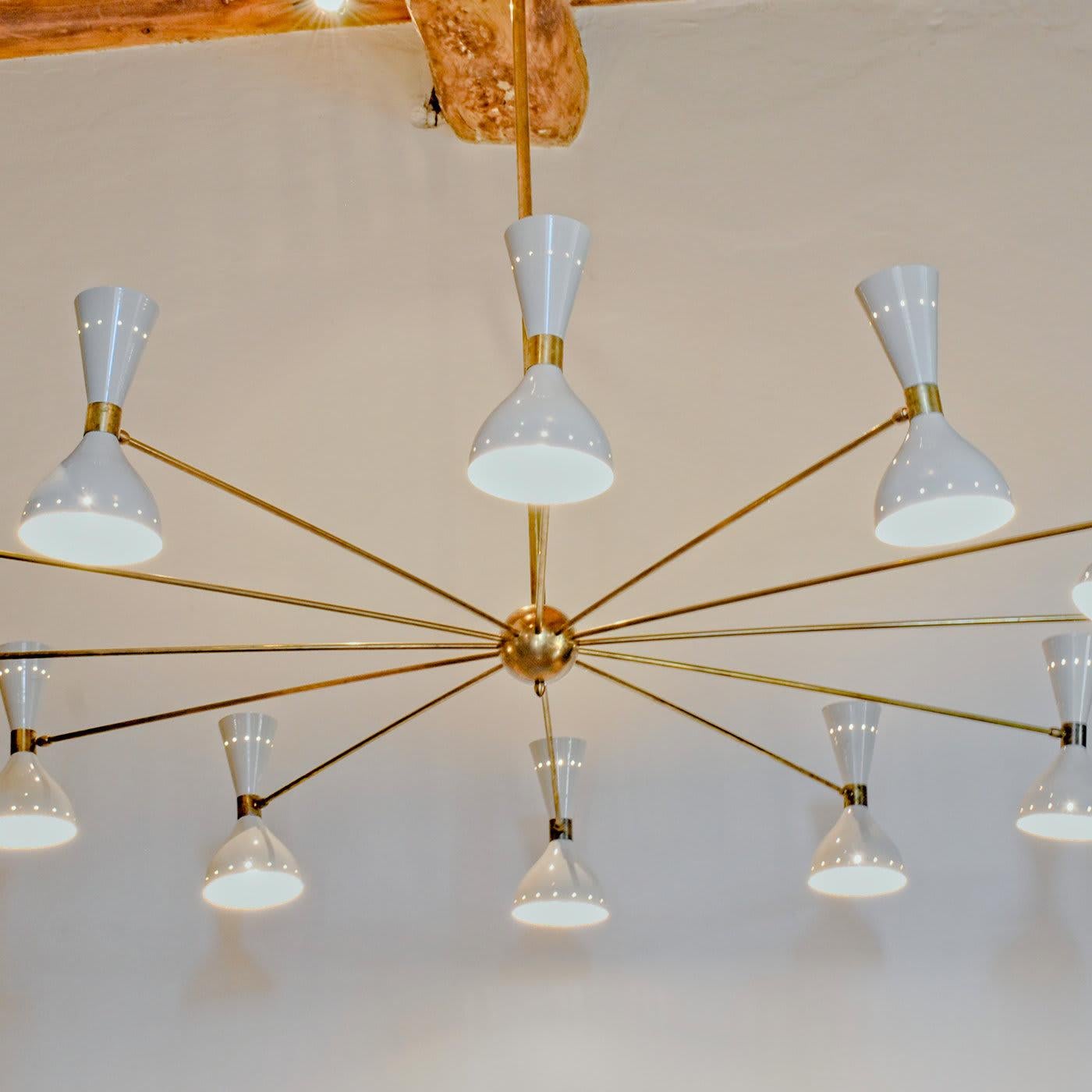 This magnificent chandelier is an imposing object of functional decor that will add luxury and elegance to a modern living room, loft space or hotel foyer. Its solid brass structure comprises a central stem with 12 arms, each supporting two aluminum