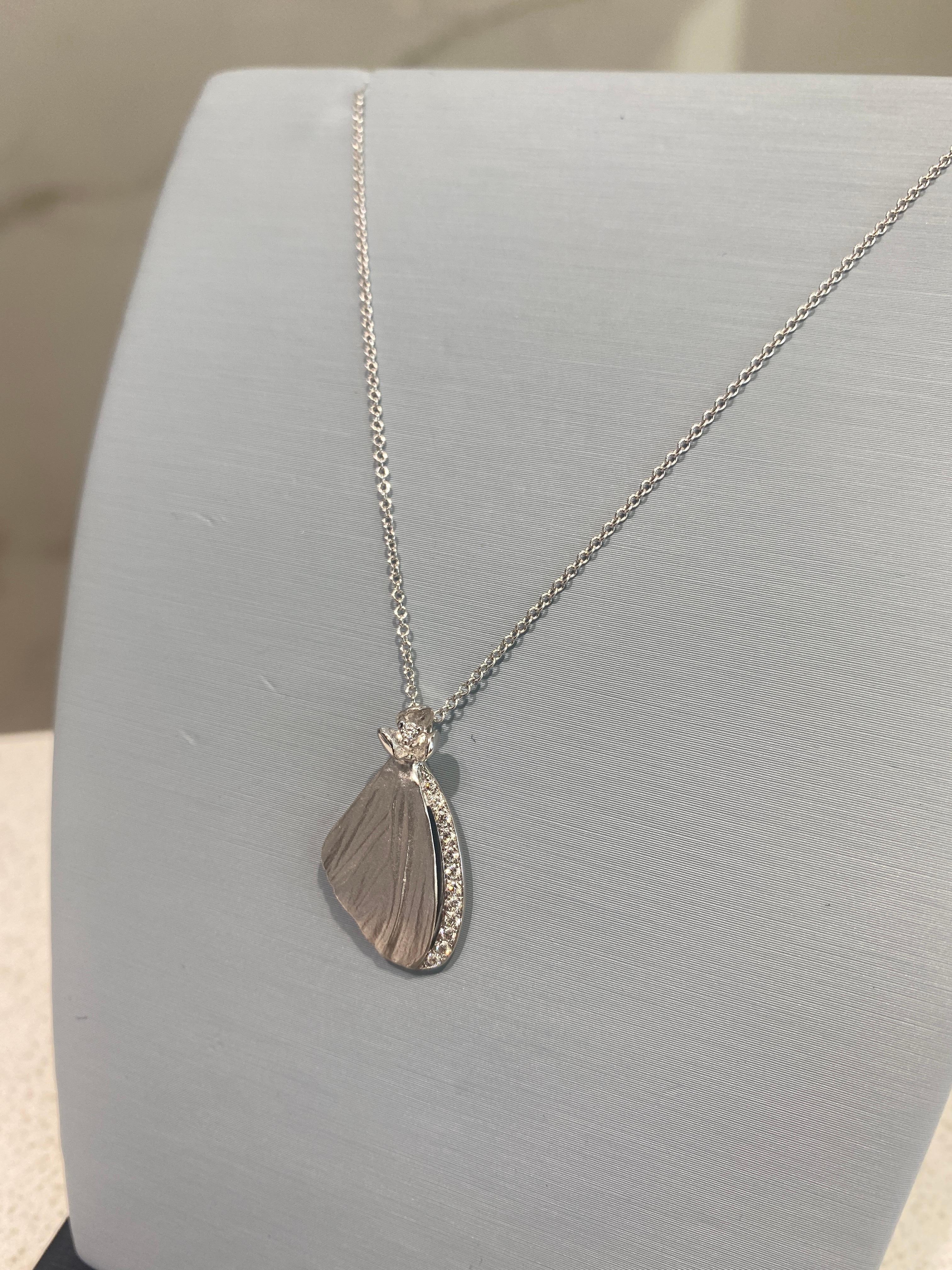 This unique pendant necklace from Simon G. features a delicate butterfly's wing crafted in 18 karat white gold and accented by a row of 0.11 carat total weight in round brilliant cut diamonds. It is set on an 18 karat white gold 18