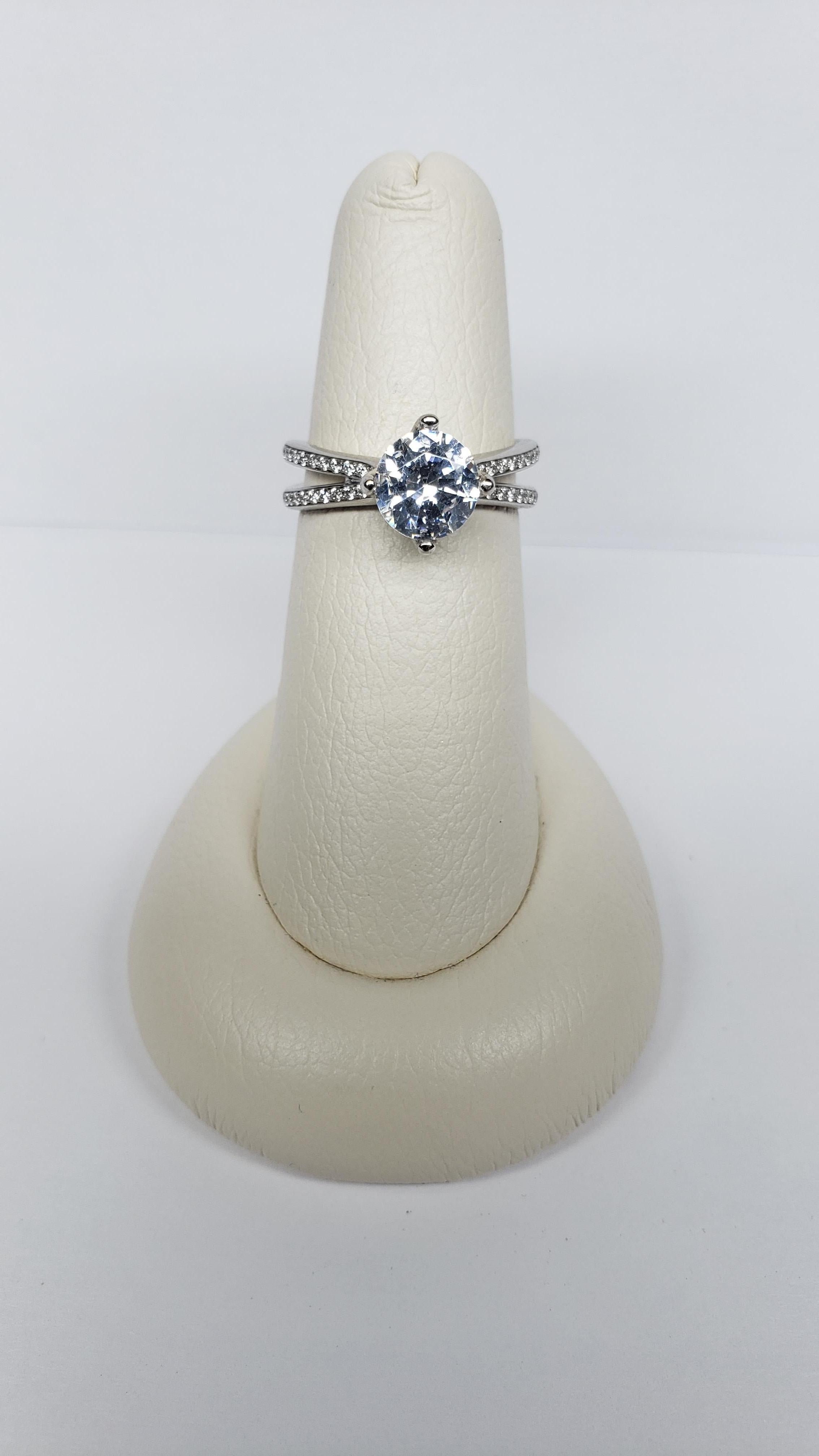 This semi mount is made from 18k white gold and was designed by Simon G. It features an elongated split shank with pave diamonds along the upper half. Diamonds also adorn the two split prongs on either side of the head. The total diamond weight is