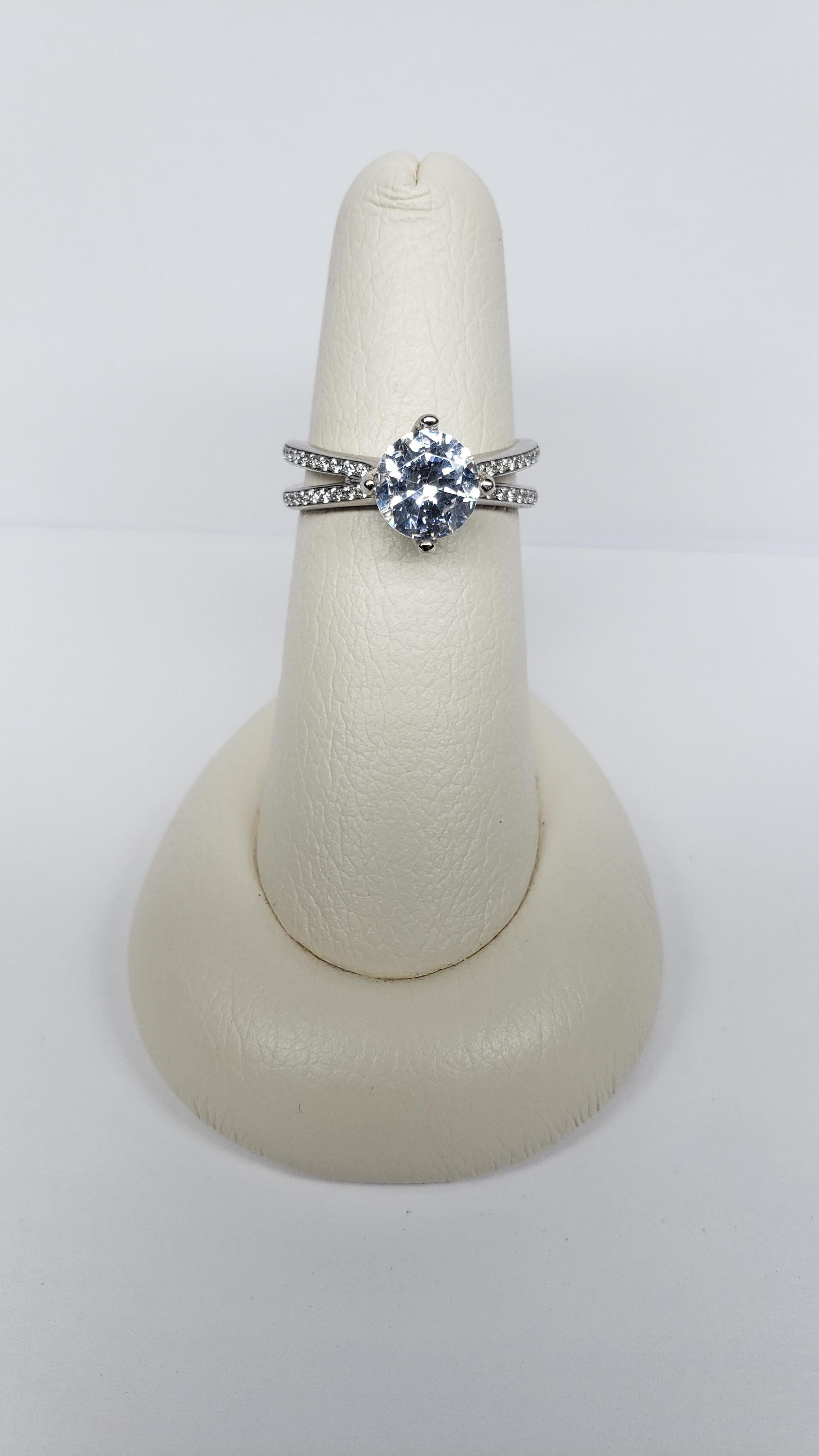 This semi mount is made from 18k white gold and was designed by Simon G. It features an elongated split shank with pave diamonds along the upper half. Diamonds also adorn the two split prongs on either side of the head. The total diamond weight is