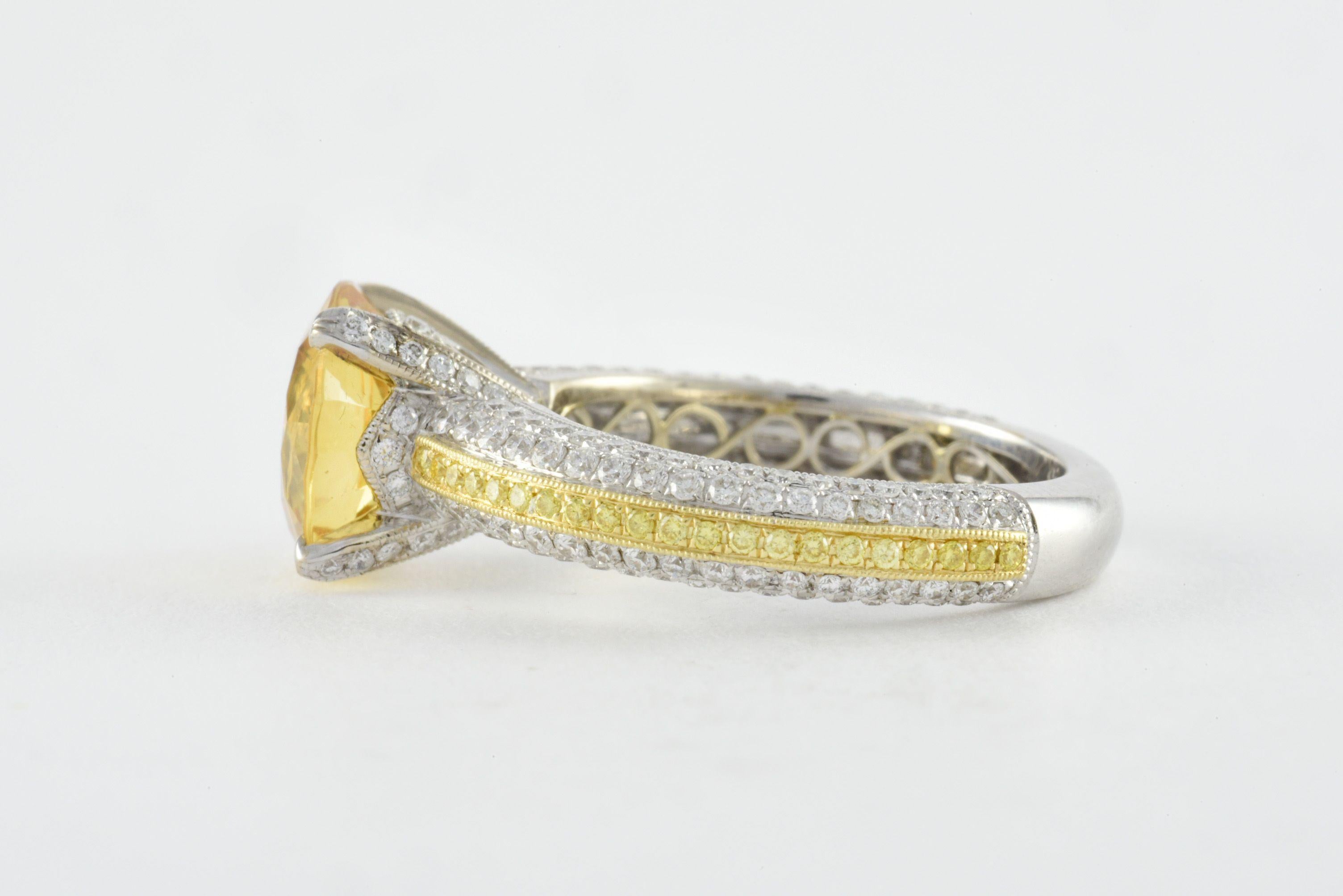 A natural unheated round shaped yellow sapphire measuring approximately 9.61mm sits at the center of this stunning ring by jeweler Simon G. and embellished with a mix of round white diamonds totaling 0.88 carats and fancy yellow diamonds totaling