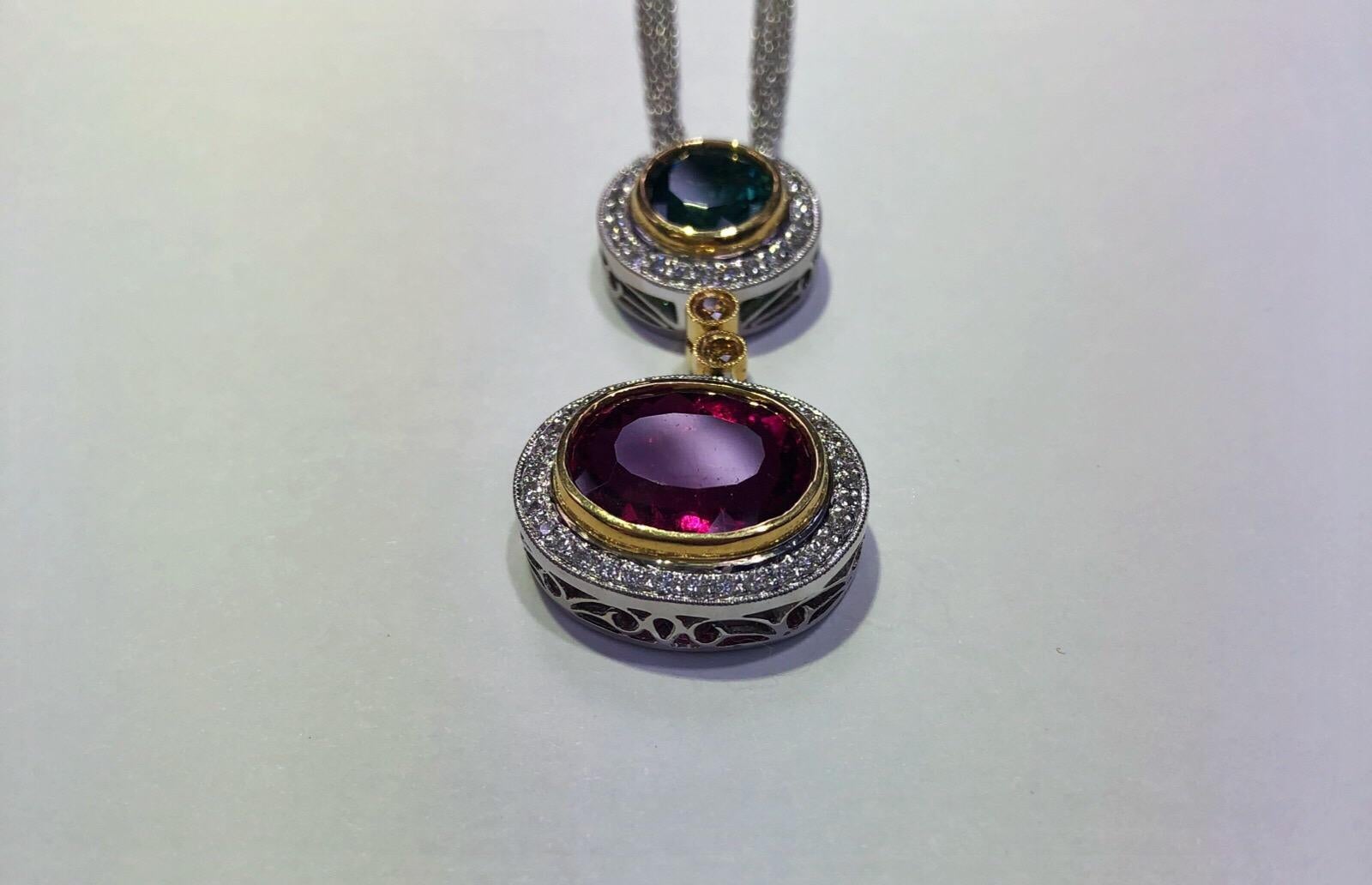 18k white and yellow gold Simon G pendant set with one bezel-set 5.41 carat oval cut Rubelite center, one bezel-set 1.63 carat round green tourmaline center. Has a 0.07 carat total weight of two round brilliant yellow diamonds, and 0.56 carats total